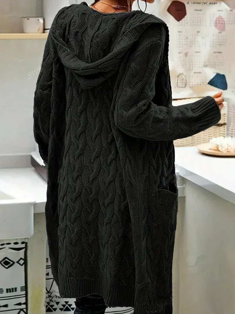 Person wearing a long black cable knit cardigan from Meleche or Meléche (short as (Mé))