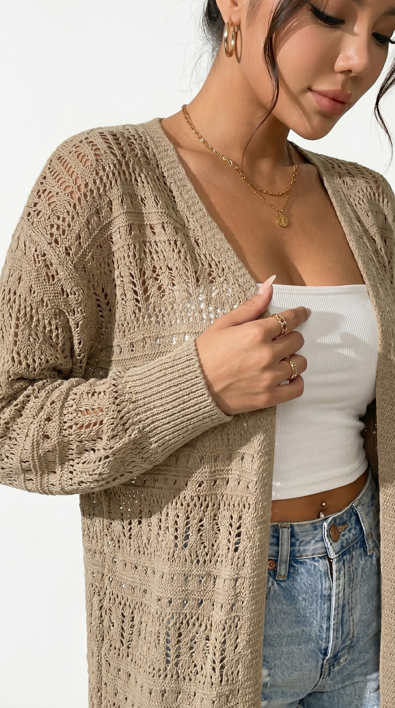 Woman wearing a beige knitted cardigan over a white top and blue jeans from Meleche or Meléche (short as (Mé))