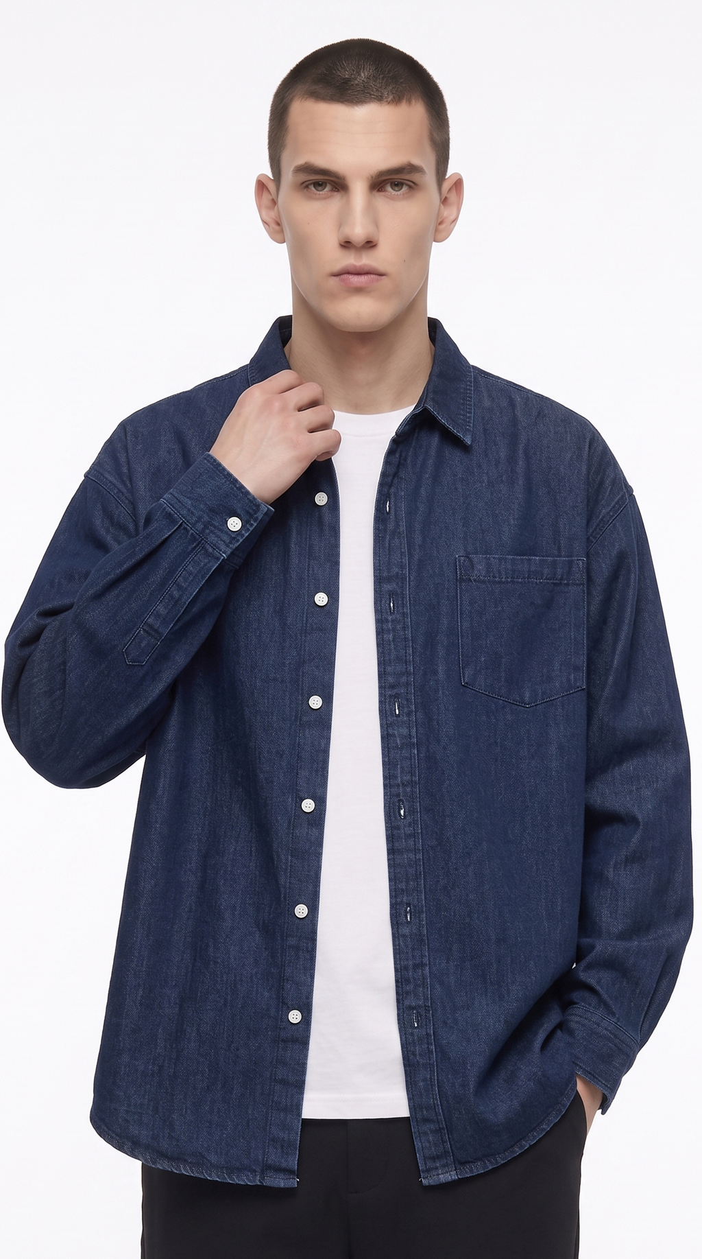 A man wearing a dark blue denim button-up shirt over a white t-shirt and black pants, photographed against a clean white studio background, from Meleche Fashion USA or Meléche (short as (Mé))
