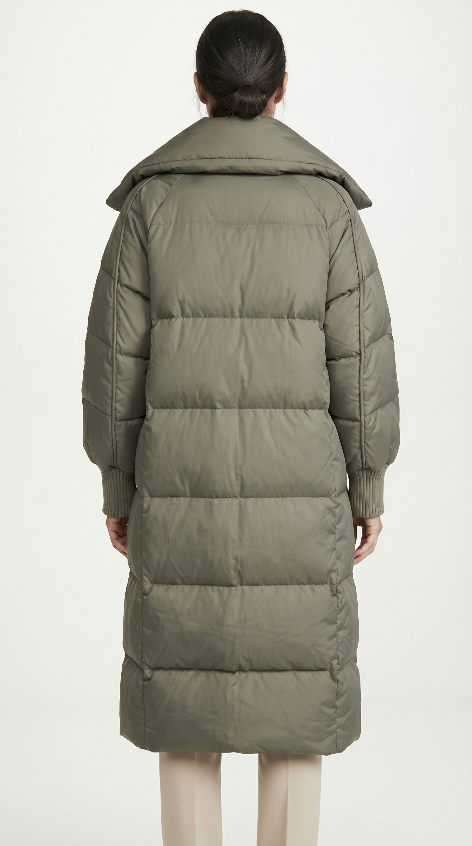 Person wearing a long olive green puffer coat on a white background from Meleche USA or Meléche (short as (Mé))