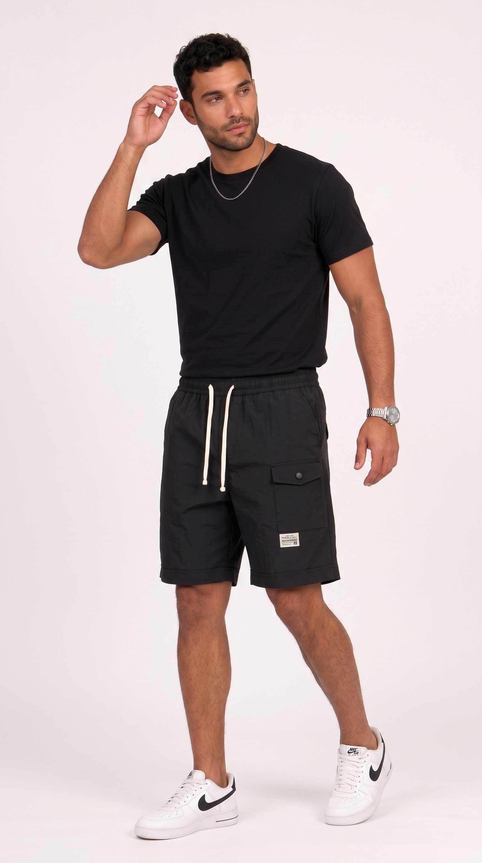 A man modeling black cargo shorts with white drawstrings, paired with a black t-shirt and white sneakers, standing against a plain light background, from Meleche Fashion USA or Meléche (short as (Mé))