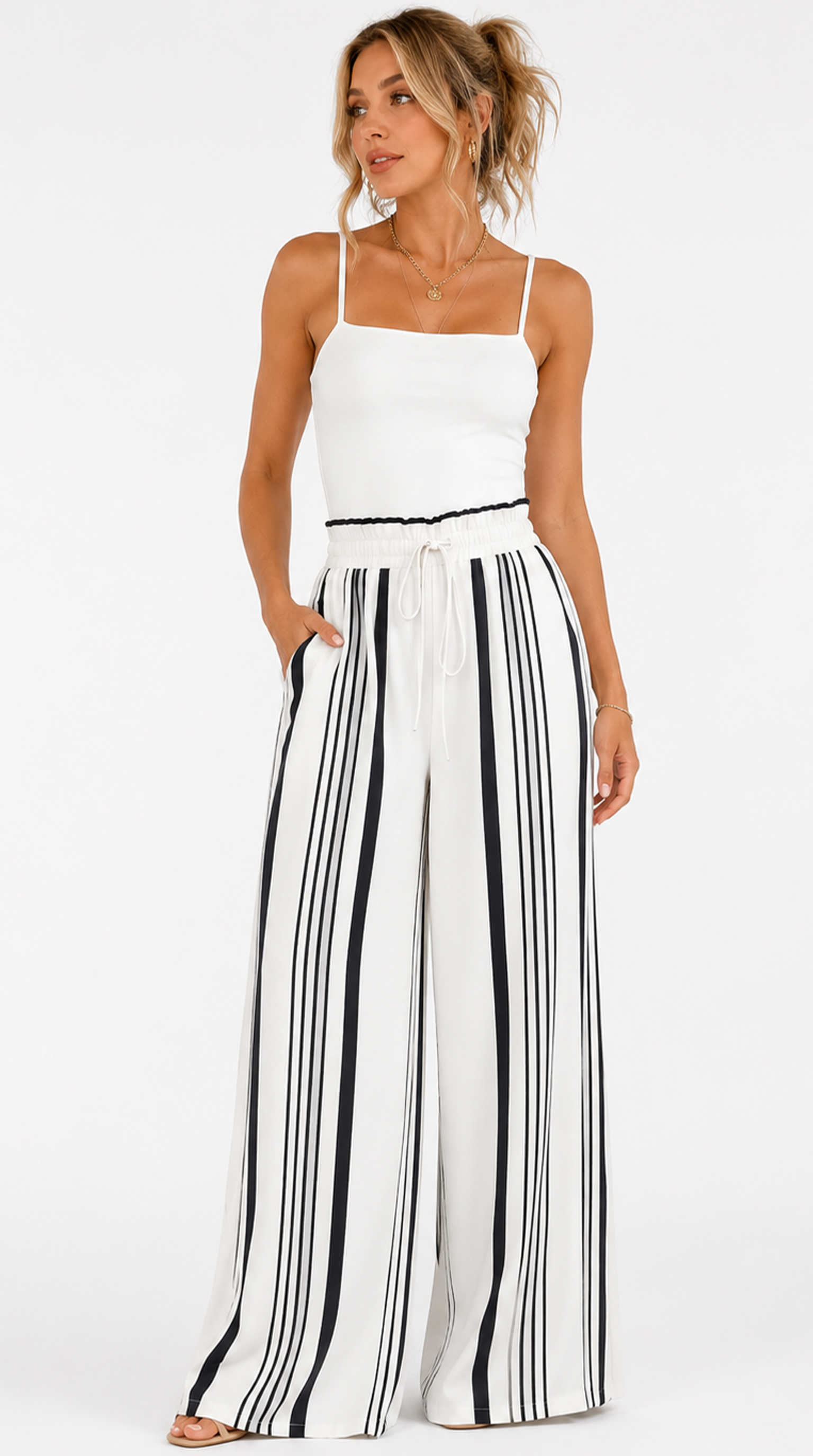 Woman wearing a white top and black and white striped pants on a white background