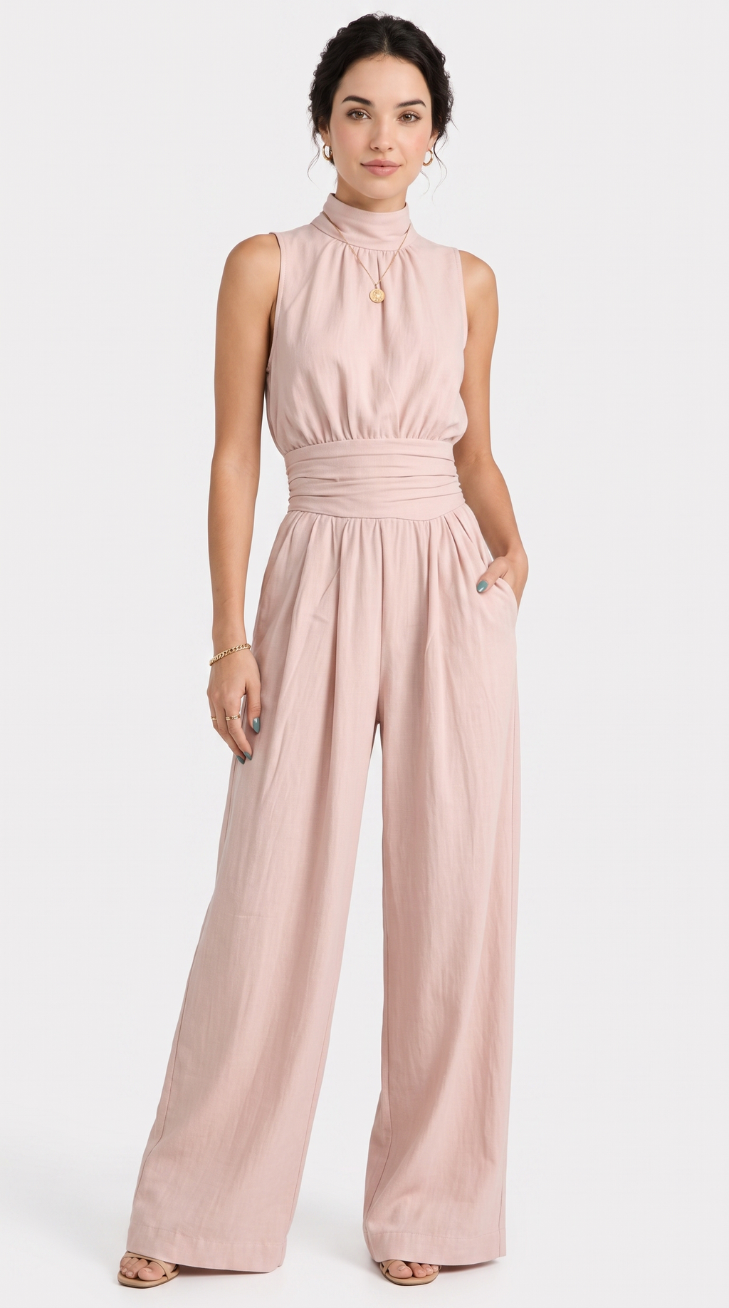A woman modeling a sleeveless high-neck jumpsuit in a dusty pink color, featuring a gathered waist and wide legs, set against a plain light gray background, from Meleche Fashion USA or Meléche (short as (Mé))