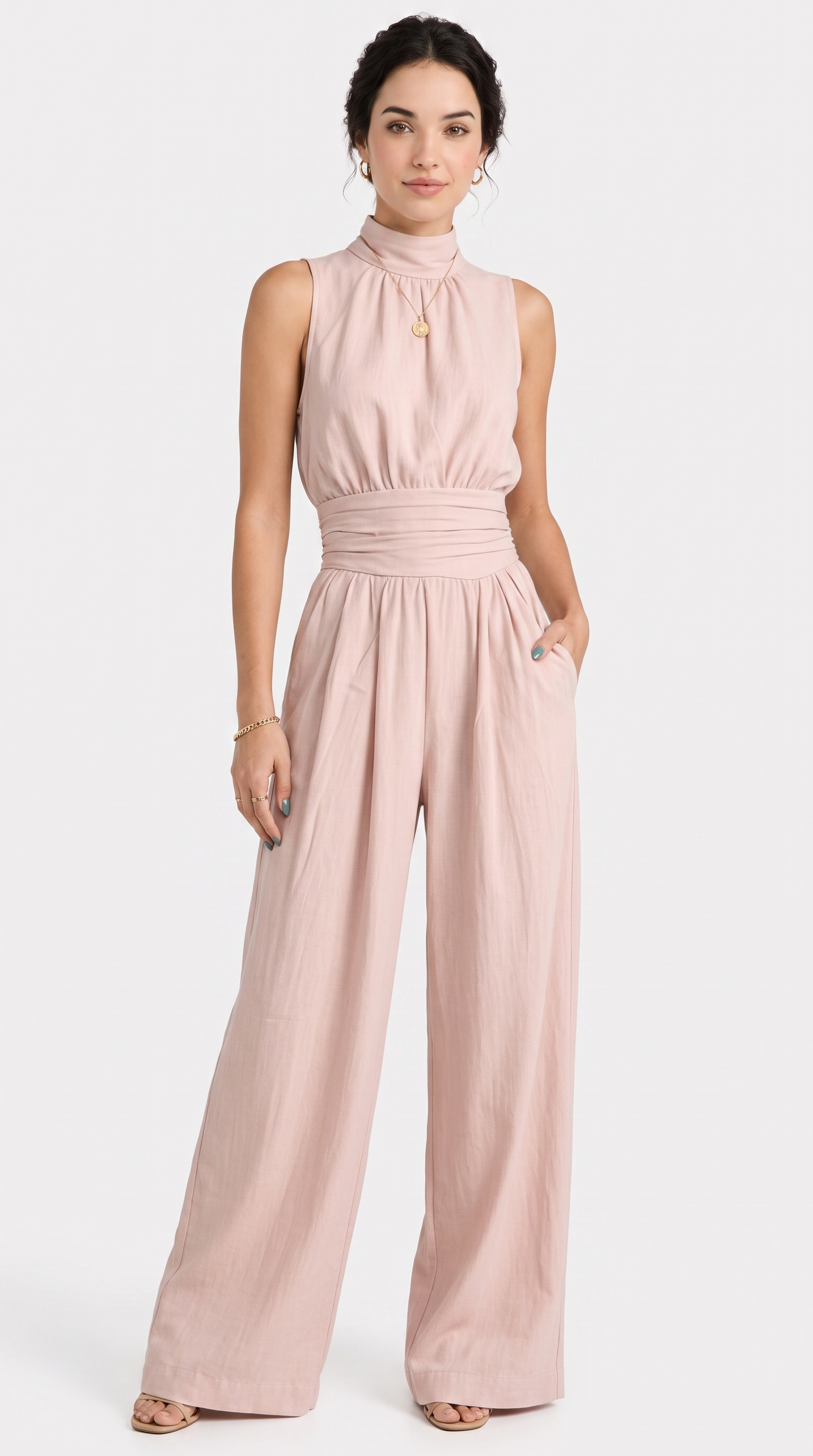 A woman modeling a sleeveless high-neck jumpsuit in a dusty pink color, featuring a gathered waist and wide legs, set against a plain light gray background, from Meleche Fashion USA or Meléche (short as (Mé))