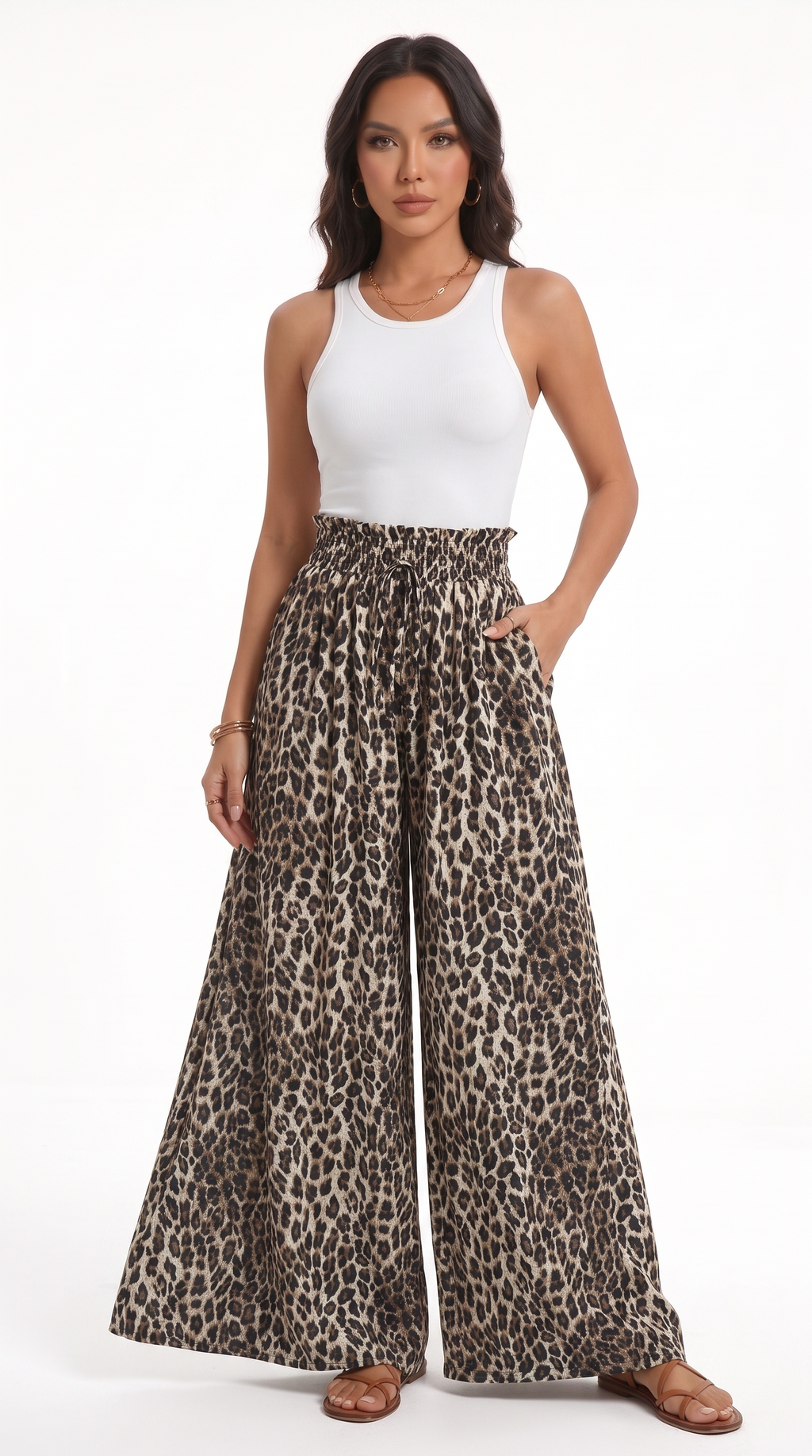 A woman modeling a pair of high-waisted, wide-leg pants with a brown and black leopard print pattern, paired with a white tank top and brown sandals, against a plain white studio background, from Meleche Fashion USA or Meléche (short as (Mé))