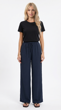 Woman wearing a black top and navy wide-leg pants on a white background, sexy loss pants from Meleche Fashion USA or Meléche (short as (Mé))