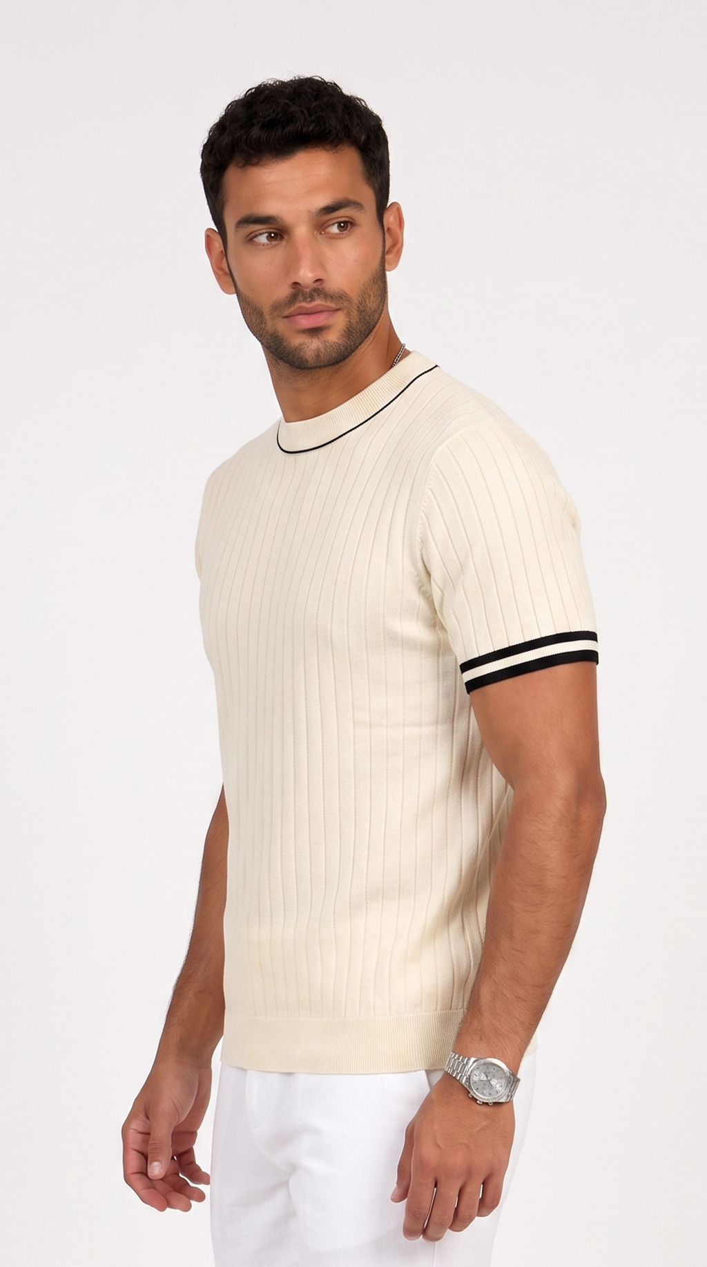 A man wearing a cream-colored ribbed short-sleeve knit sweater with black trim at the crew neck and sleeve cuffs, paired with white trousers, against a plain light background, from Meleche Fashion USA or Meléche (short as (Mé))