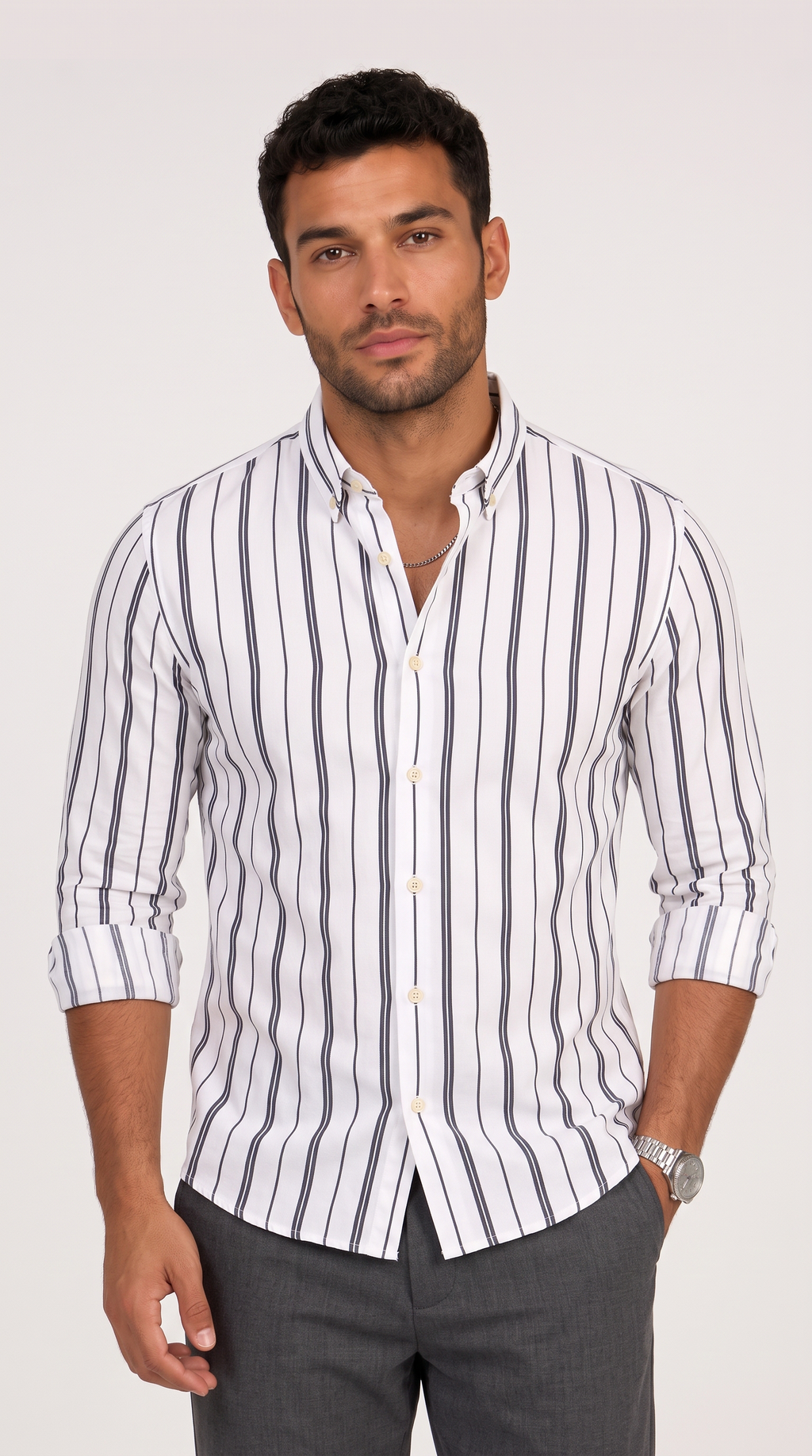 A man wearing a white long-sleeve button-down shirt with vertical gray stripes, paired with gray trousers, standing against a light gray studio background, from Meleche Fashion USA or Meléche (short as (Mé))