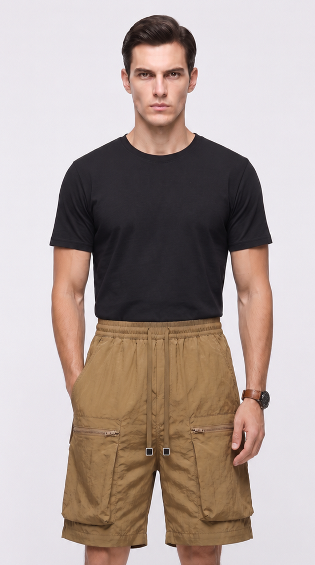 A male model wearing a black short-sleeve crewneck t-shirt and tan cargo shorts against a light gray studio background, from Meleche Fashion USA or Meléche (short as (Mé))