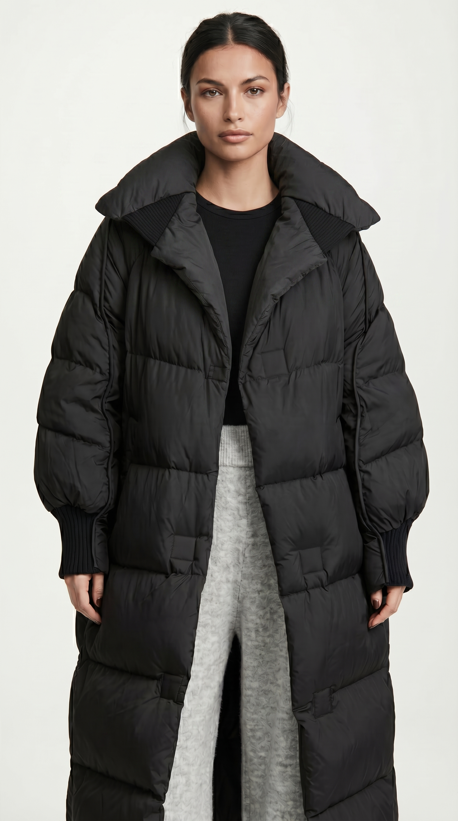 Woman wearing a long black puffer coat on a white background from Meleche or Meléche USA (short as (Mé))
