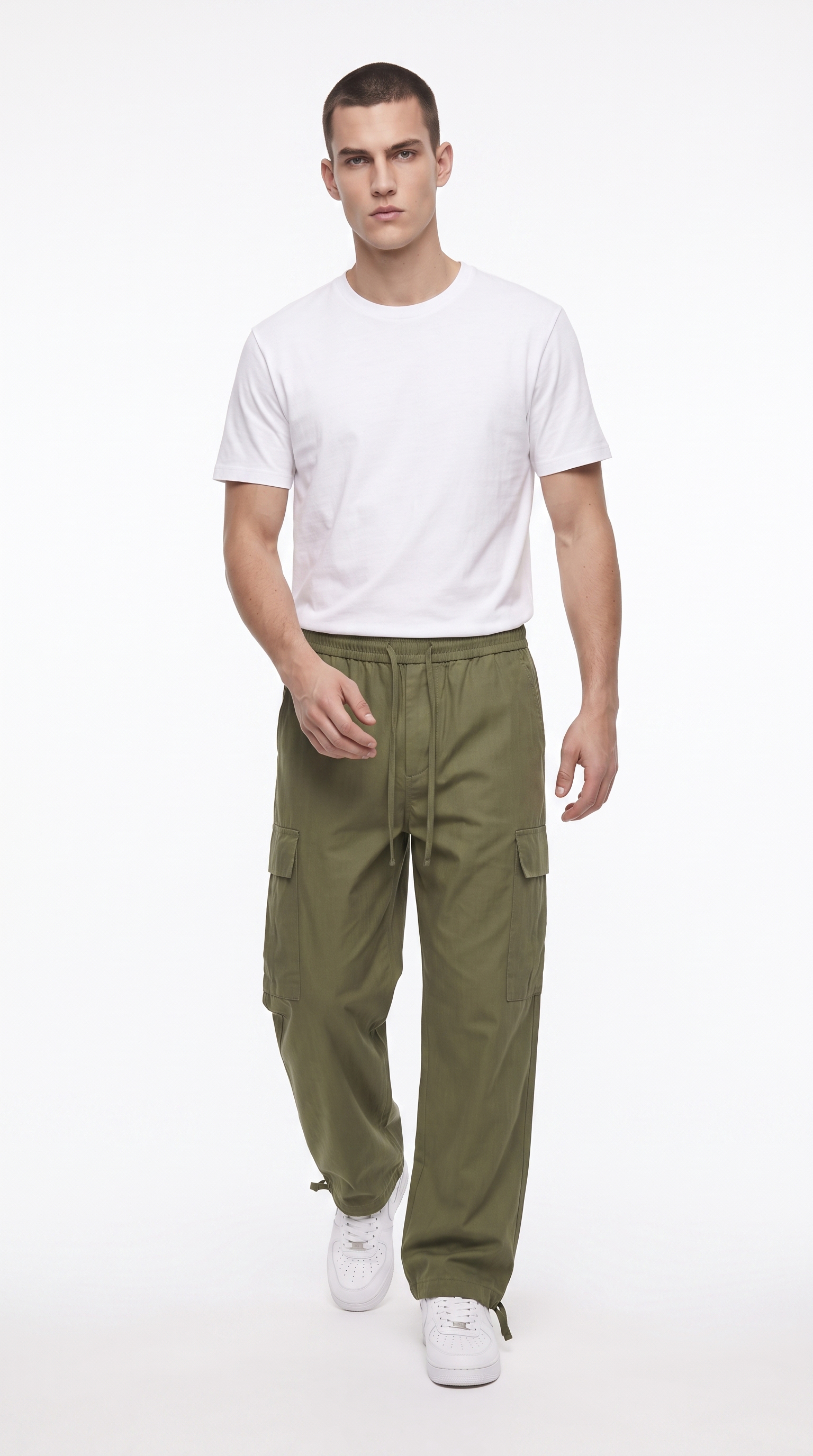 A man modeling a white crew-neck t-shirt and olive green cargo pants with white sneakers, shot against a plain white studio background, from Meleche Fashion USA or Meléche (short as (Mé))
