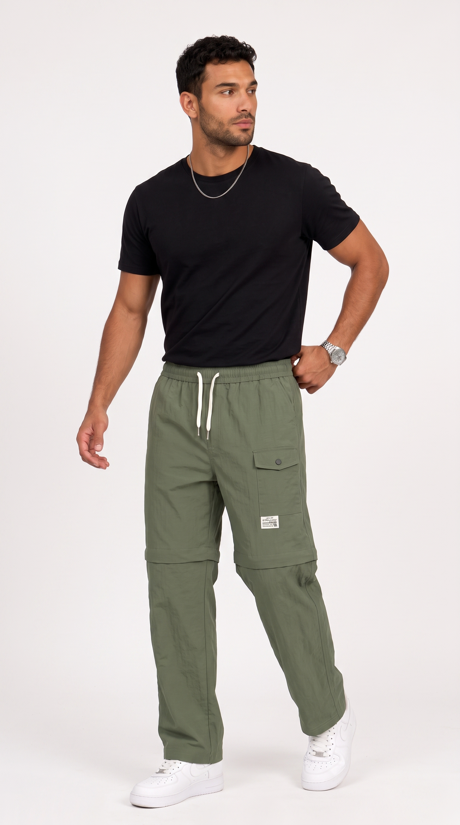 A man modeling olive green cargo pants with a black t-shirt and white sneakers, standing against a light gray studio background, from Meleche Fashion USA or Meléche (short as (Mé))