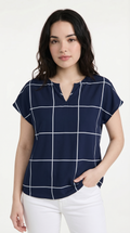 Woman wearing a navy blue checkered blouse with white pants on a white background, from Meleche Fashion USA or Meléche (short as (Mé))