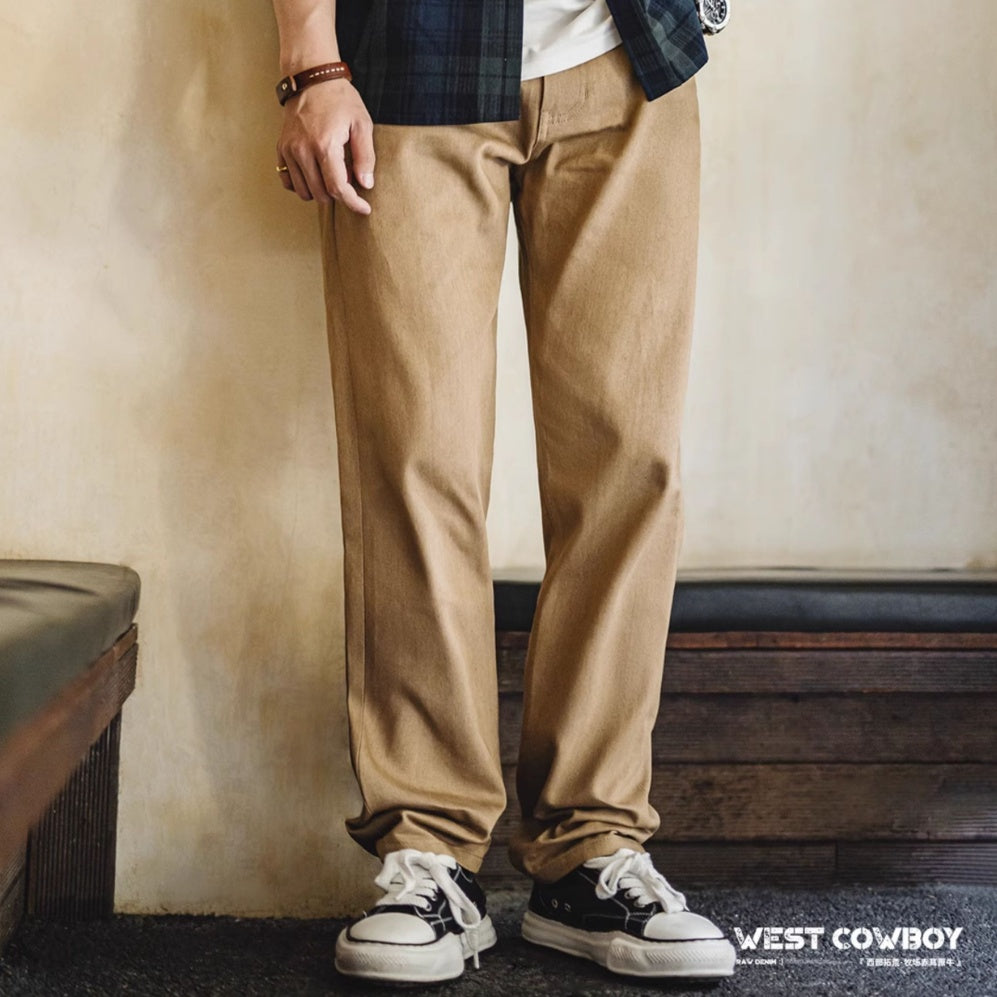 Person wearing beige pants and black and white sneakers with a plain background