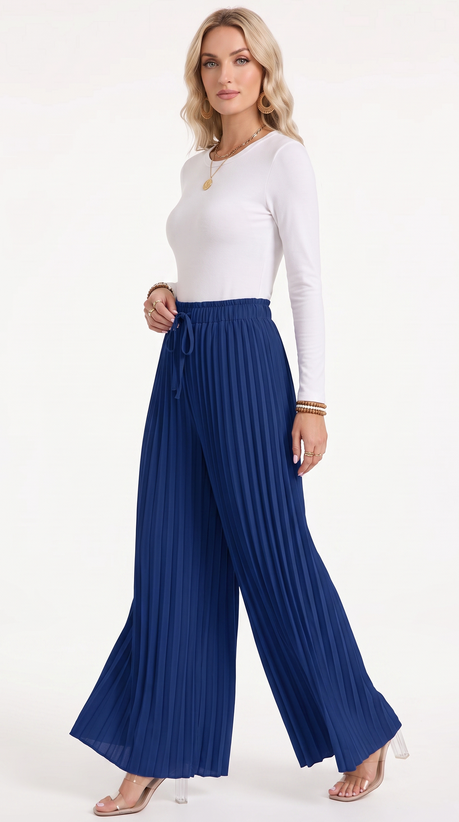 A woman modeling a white long-sleeve top and high-waisted, wide-leg pleated blue pants with a drawstring waist, posed against a clean white studio background, from Meleche Fashion USA or Meléche (short as (Mé))