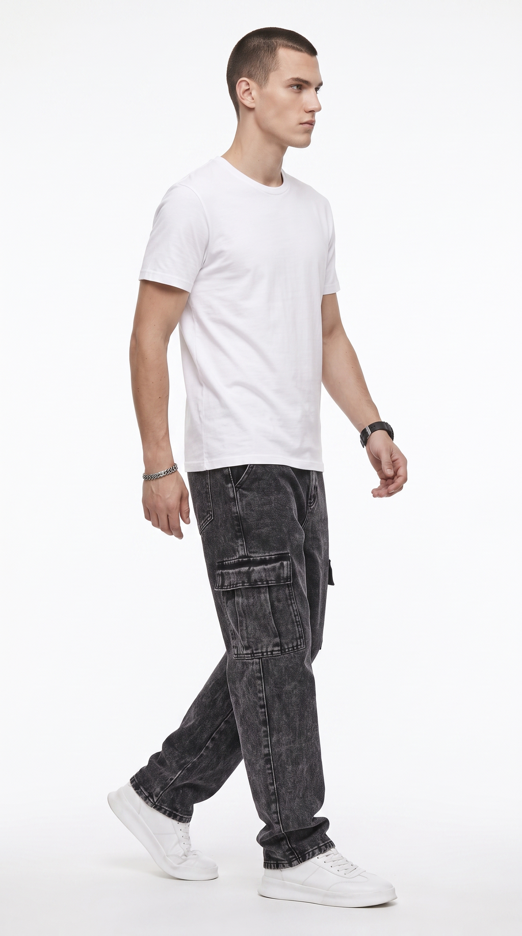 A man wearing a white crew-neck t-shirt, dark gray washed cargo jeans, and white sneakers, captured in a side-profile walking pose against a clean white studio background, from Meleche Fashion USA or Meléche (short as (Mé))
