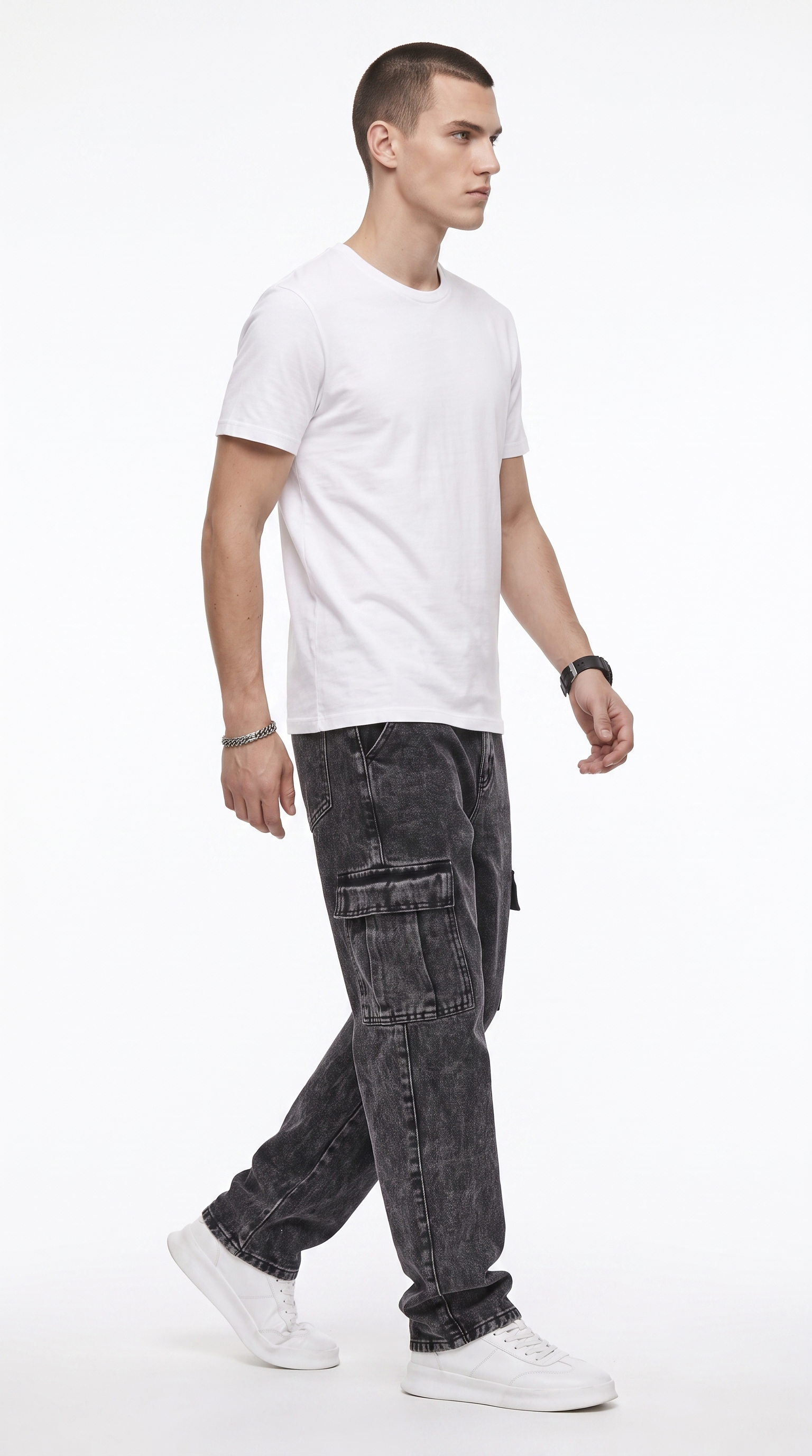 A man wearing a white crew-neck t-shirt, dark gray washed cargo jeans, and white sneakers, captured in a side-profile walking pose against a clean white studio background, from Meleche Fashion USA or Meléche (short as (Mé))