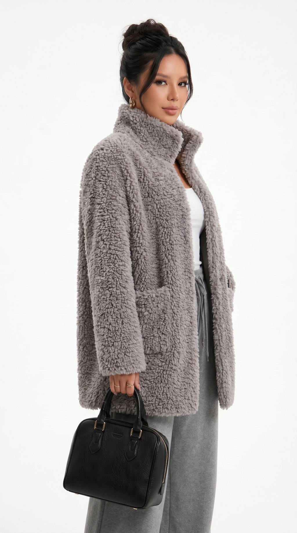 Woman wearing a gray teddy coat holding a black handbag on a white background from Meleche Fashion USA or Meléche (short as (Mé))