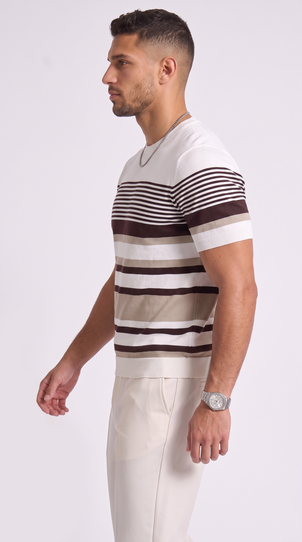 A man in profile wearing a short-sleeve crewneck t-shirt with horizontal stripes in white, beige, and dark brown, paired with light beige trousers, from Meleche Fashion USA or Meléche (short as (Mé))