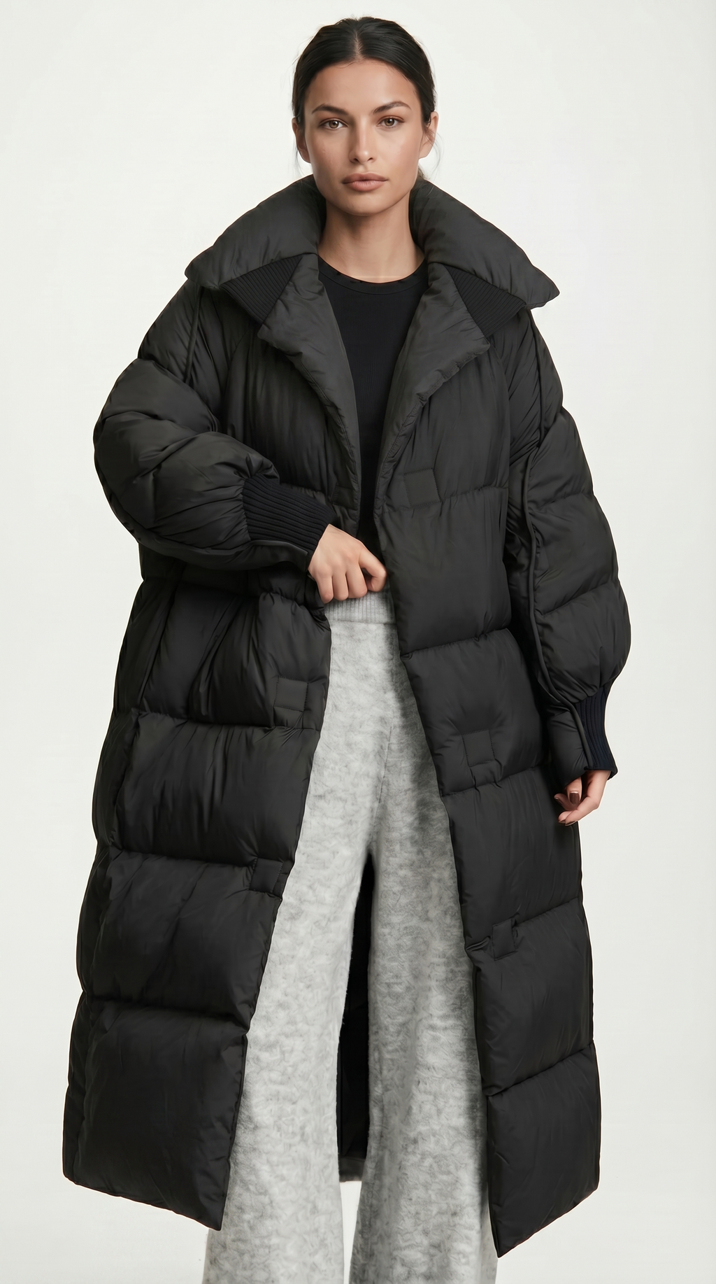 Person wearing a long black puffer coat on a white background from Meleche USA or Meléche (short as (Mé))