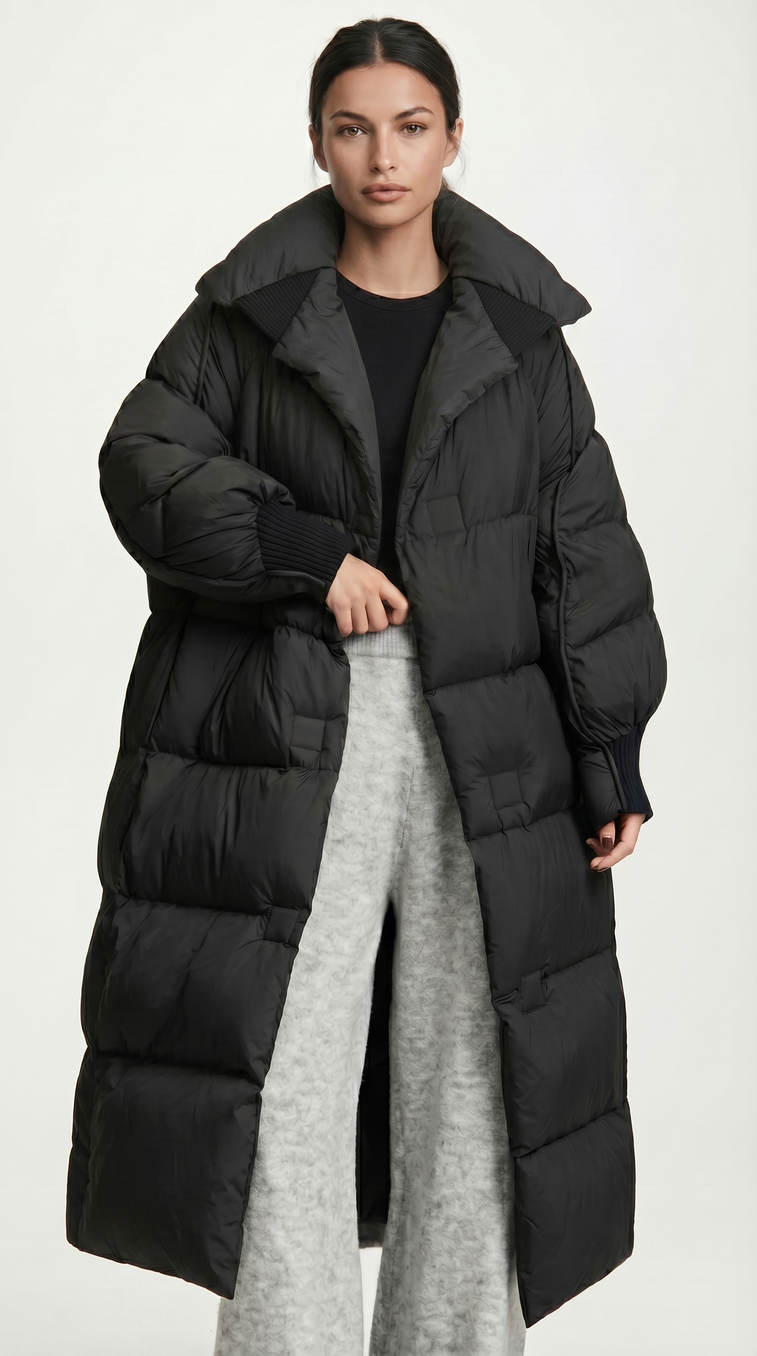 Person wearing a long black puffer coat on a white background from Meleche USA or Meléche (short as (Mé))
