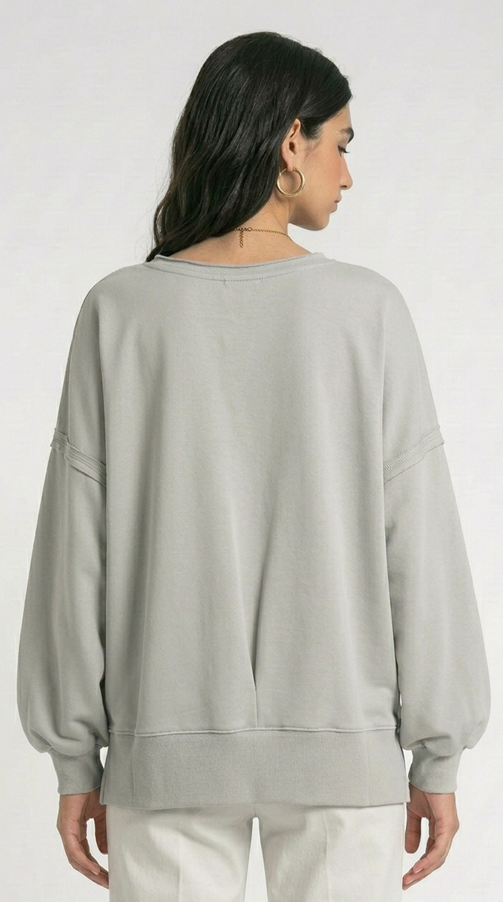 Woman wearing a white knit cardigan over a beige dress on a white background