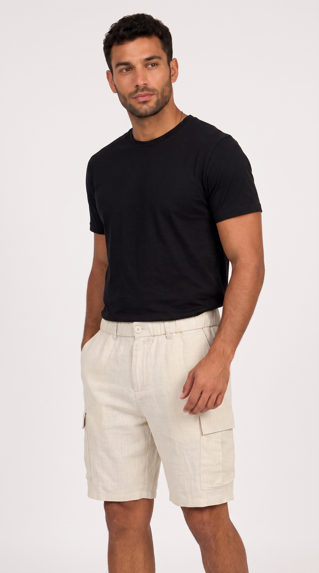 A man wearing a black short-sleeve crewneck t-shirt and light beige cargo shorts, standing against a plain light gray studio background, from Meleche Fashion USA or Meléche (short as (Mé))