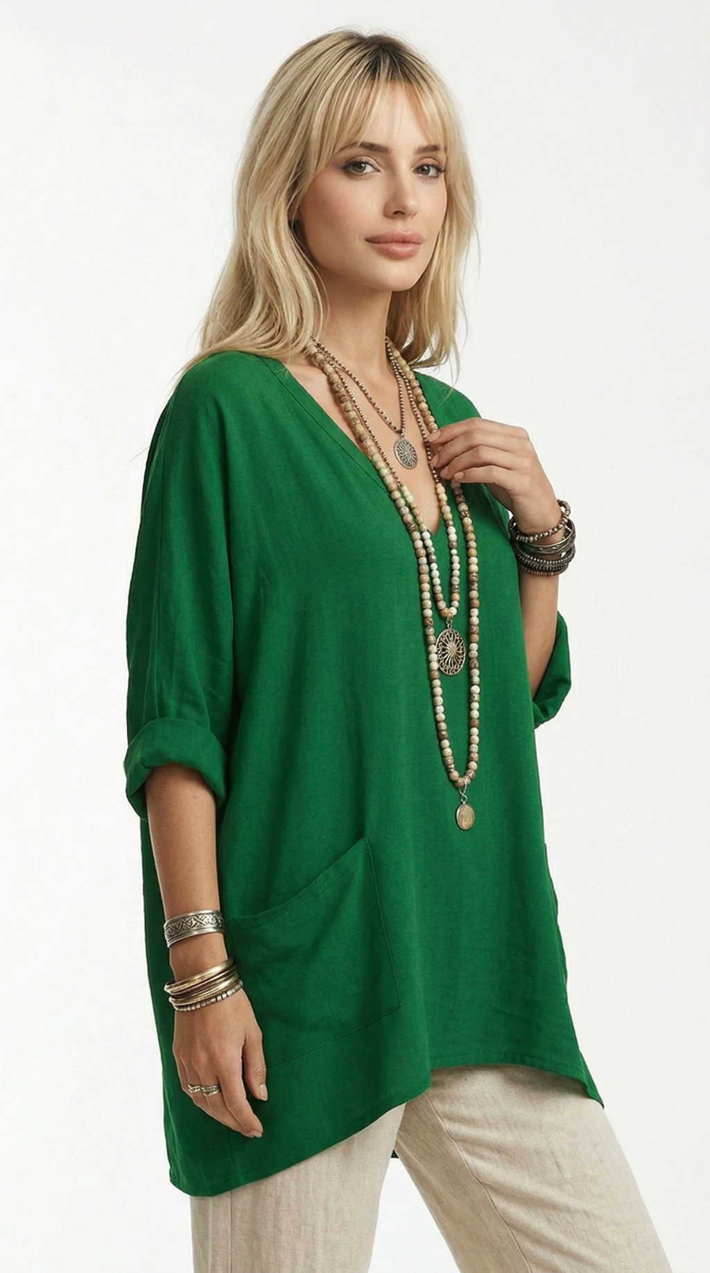 Woman wearing a green top and beige pants with layered necklaces on a white background from Meleche or Meléche (short as (Mé))