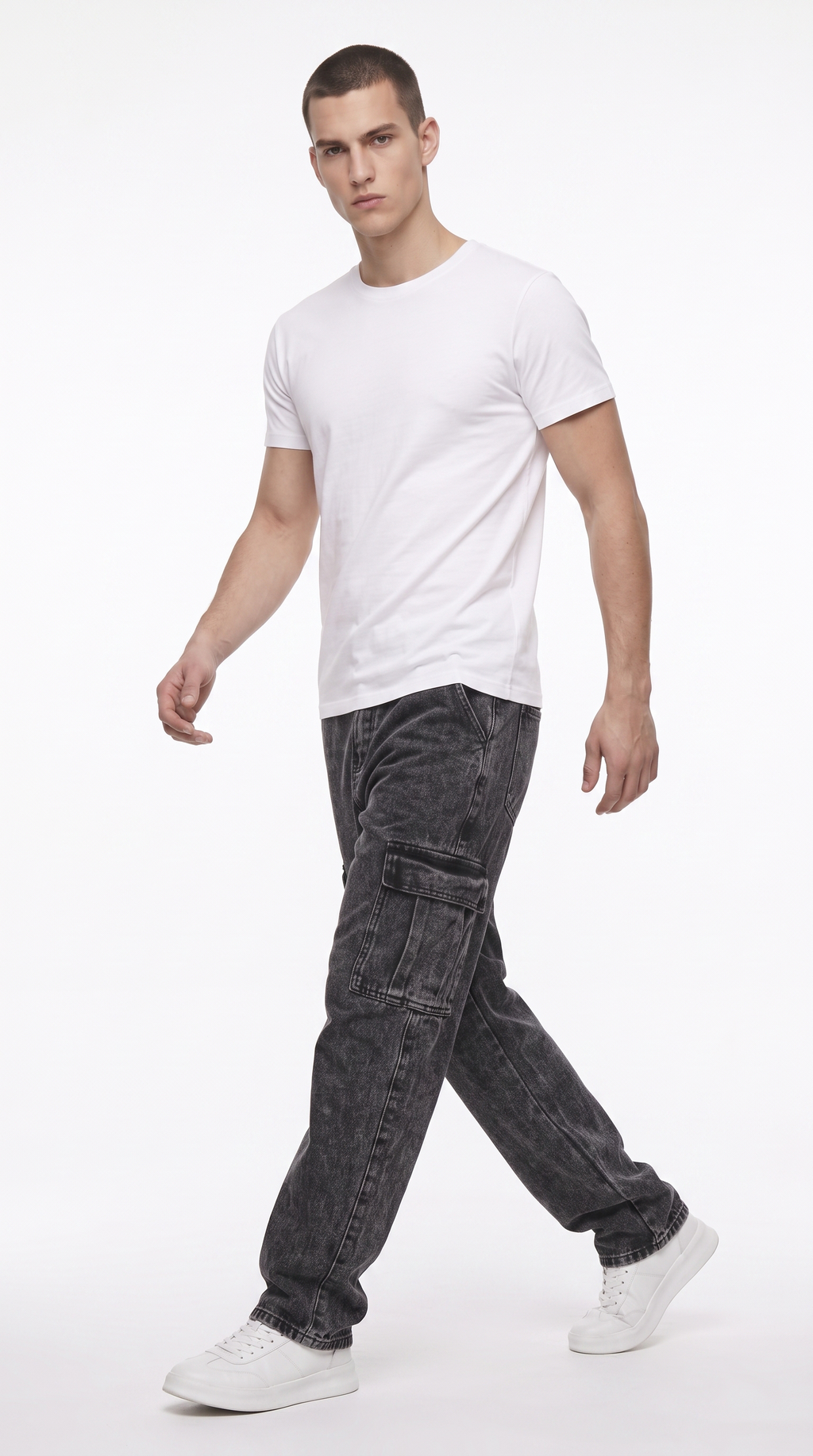 A man modeling a white crew-neck t-shirt and dark gray washed cargo jeans with white sneakers, captured in a side-profile walking pose against a clean white studio background, from Meleche Fashion USA or Meléche (short as (Mé))