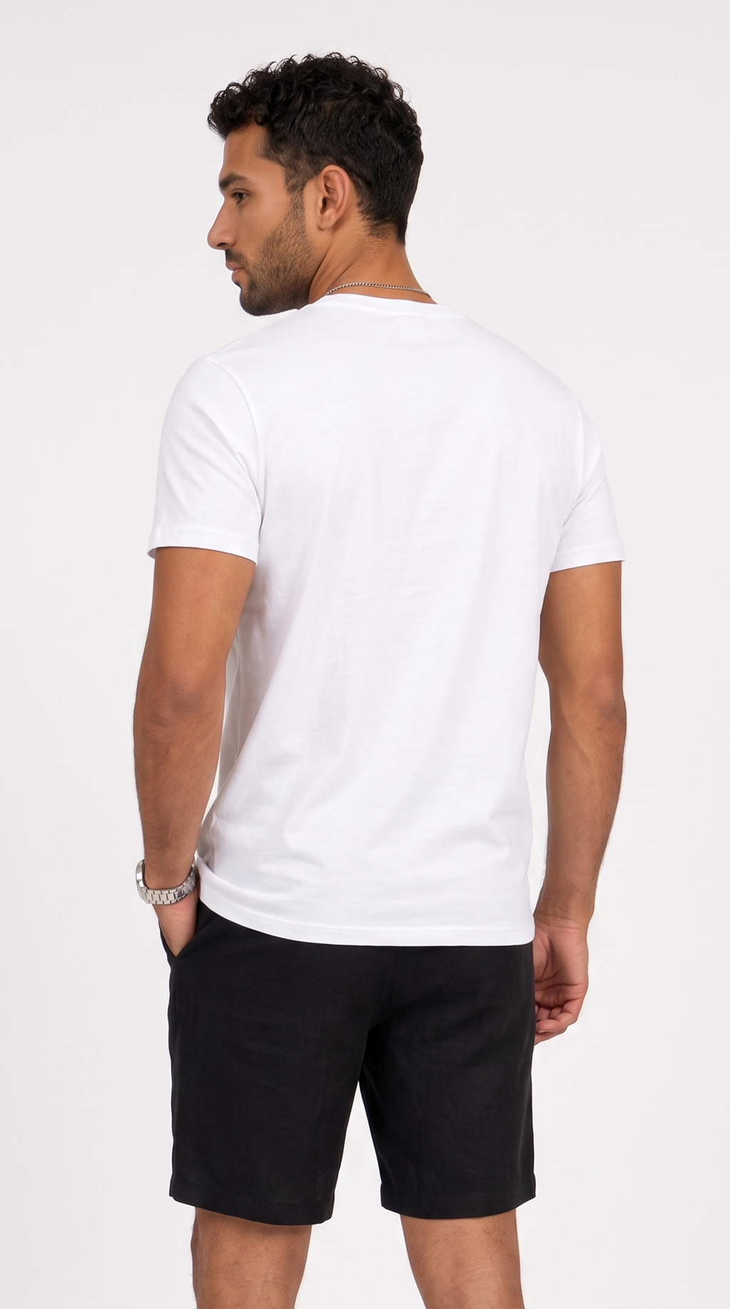 A man shown from the back wearing a plain white short-sleeve crewneck t-shirt and black shorts, standing against a light gray studio background, from Meleche Fashion USA or Meléche (short as (Mé))