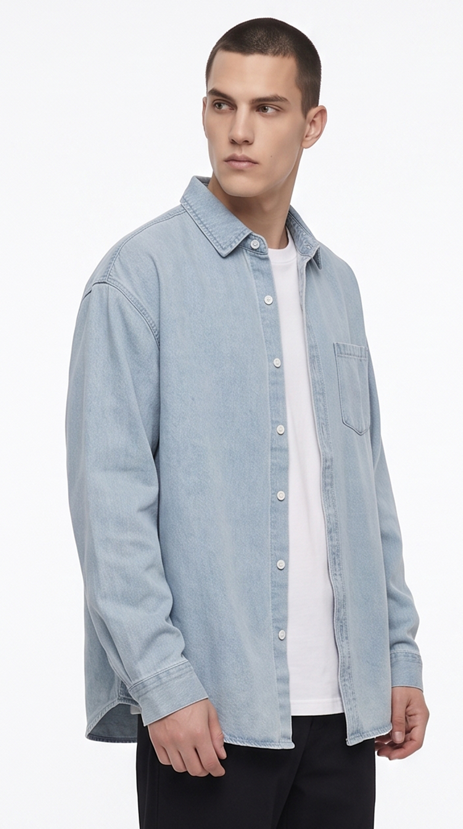 A man wearing a light blue denim button-up shirt over a white t-shirt and black pants, photographed against a clean white studio background, from Meleche Fashion USA or Meléche (short as (Mé))