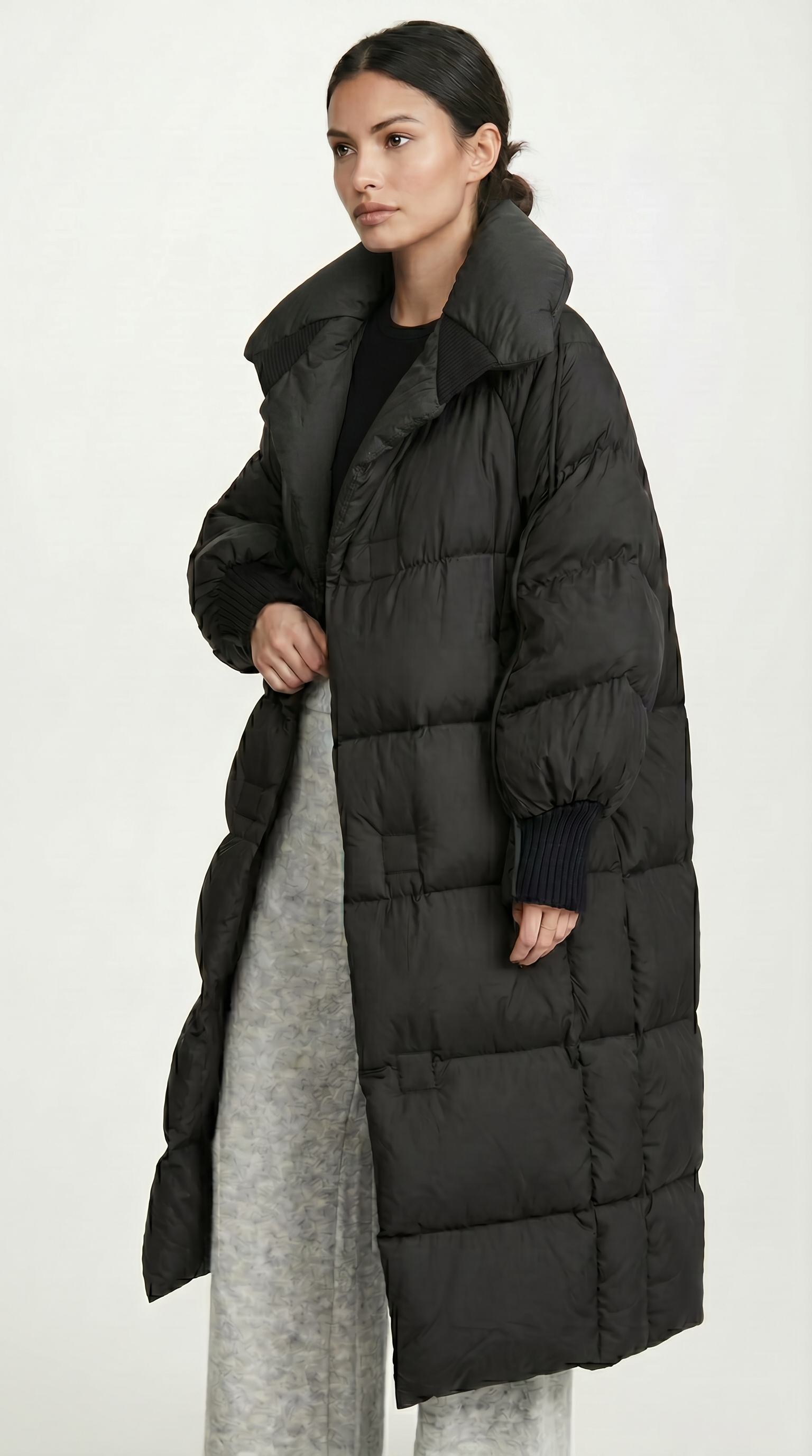 Woman wearing a long black puffer coat on a white background from Meleche USA or Meléche (short as (Mé))