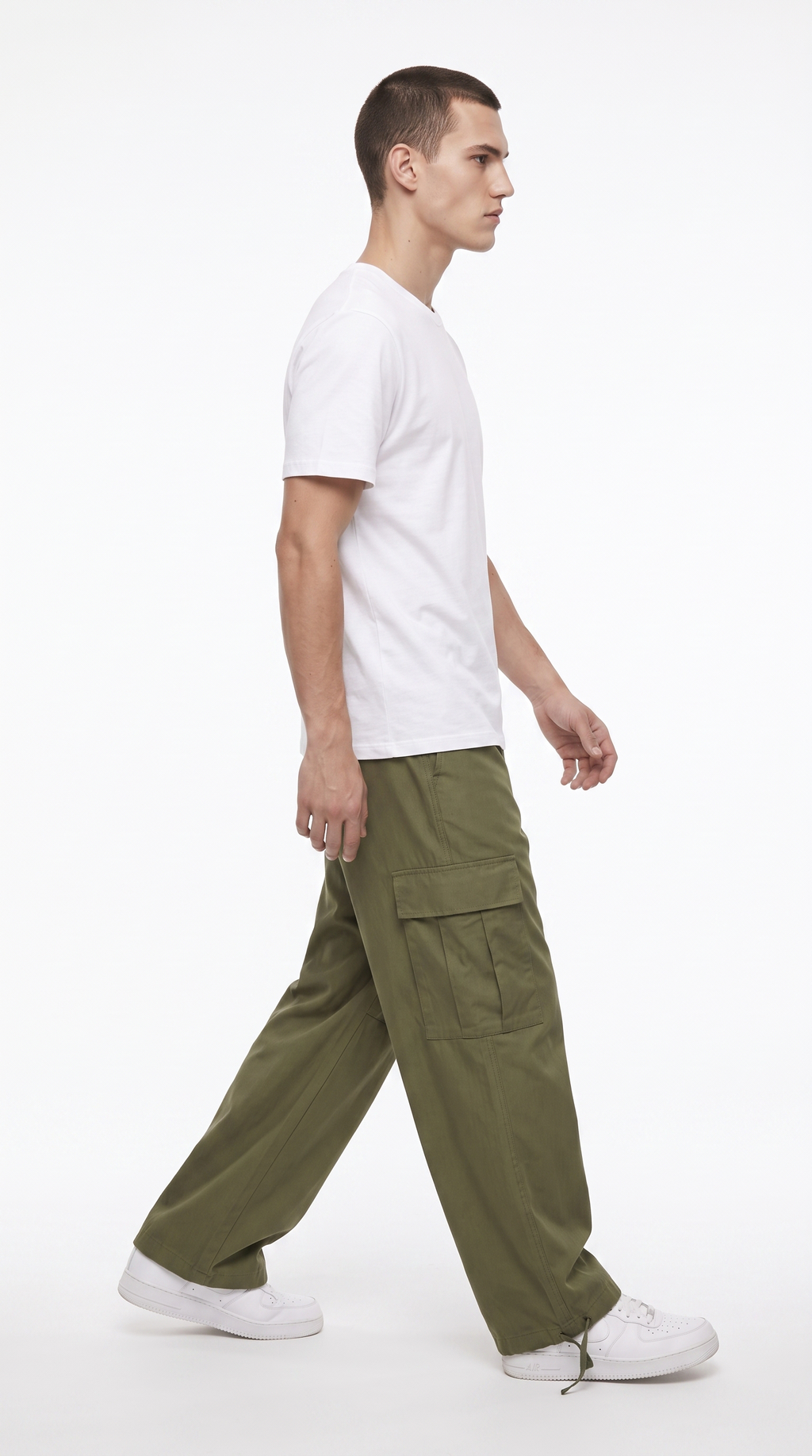 A man in profile wearing a white t-shirt, olive green cargo pants, and white sneakers, walking against a plain white studio background, from Meleche Fashion USA or Meléche (short as (Mé))