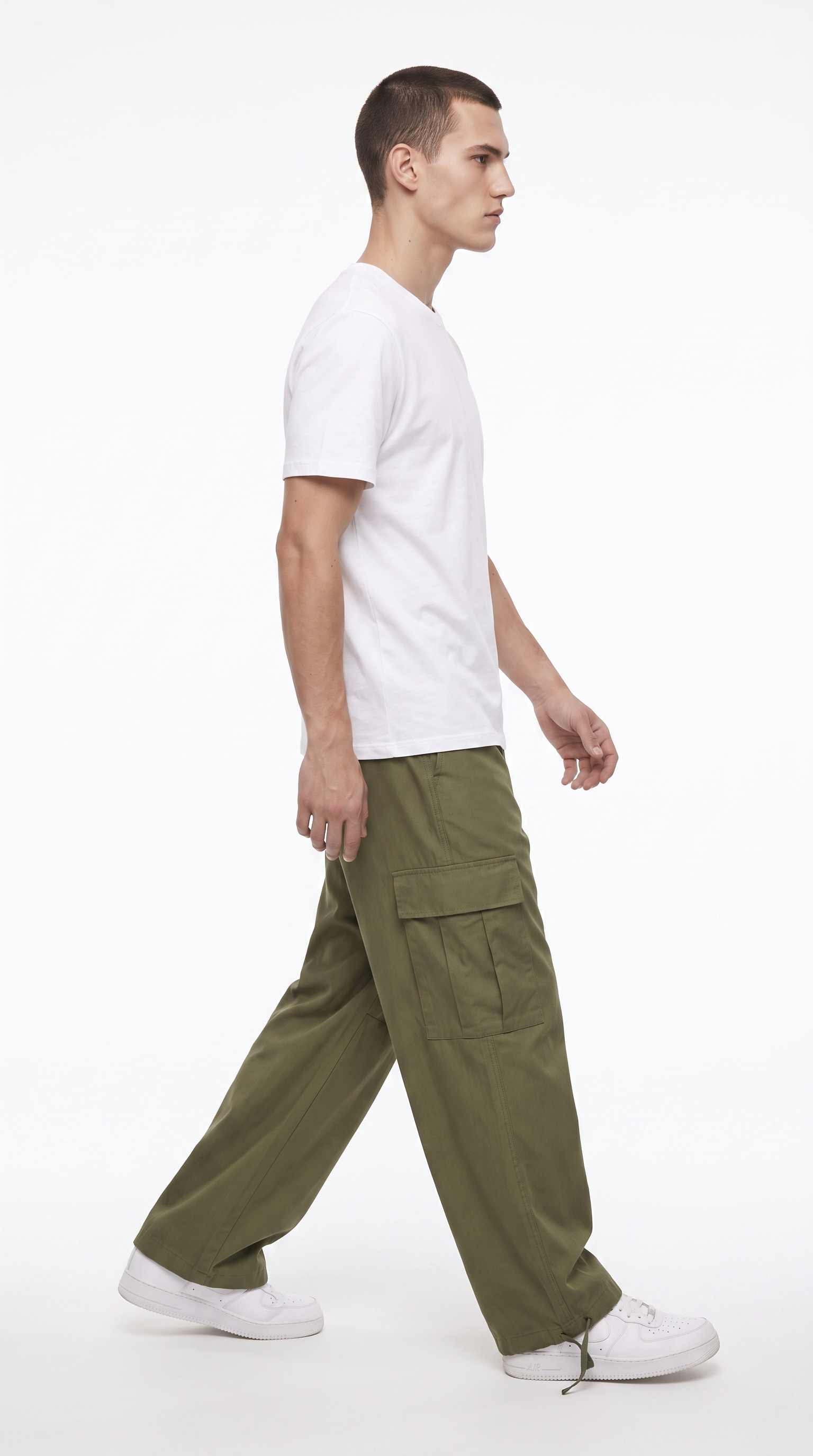 A man in profile wearing a white t-shirt, olive green cargo pants, and white sneakers, walking against a plain white studio background, from Meleche Fashion USA or Meléche (short as (Mé))