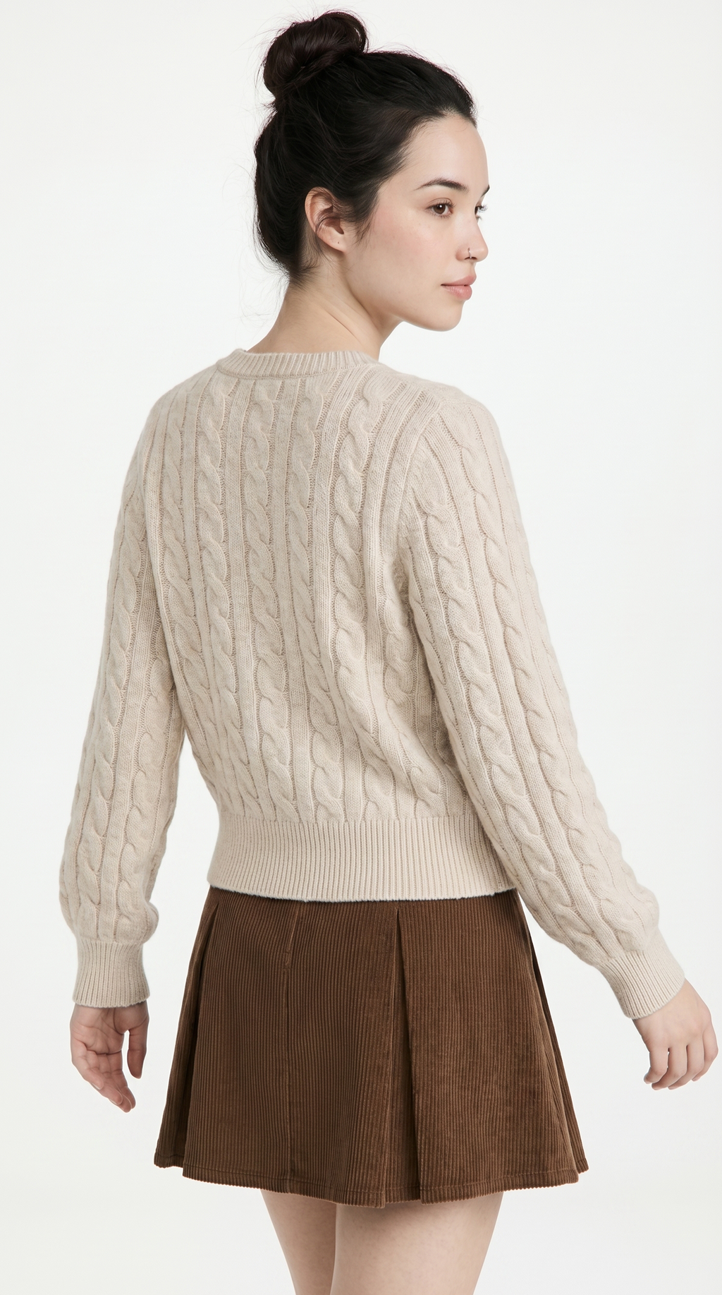 Woman wearing a beige cable knit sweater and brown pleated skirt on a white background from Meleche or Meléche (short as (Mé))