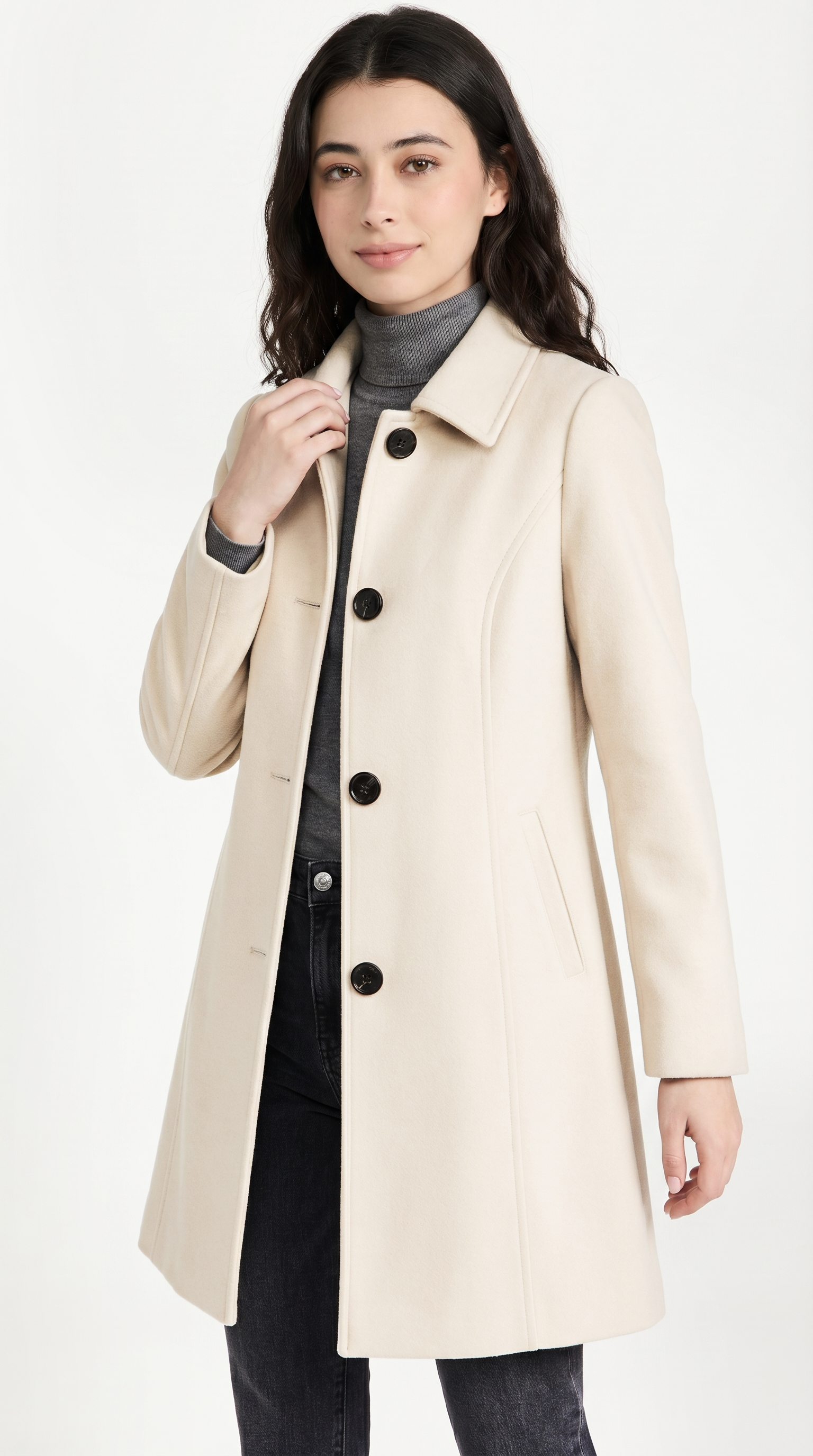 Woman wearing a beige coat with black buttons on a white background from Meleche USA or Meléche (short as (Mé))