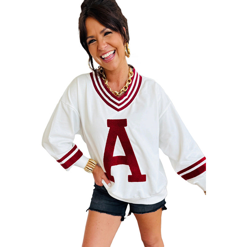 Woman wearing a white sweater with a red 'A' and denim shorts from Meleche or Meléche (short as (Mé))