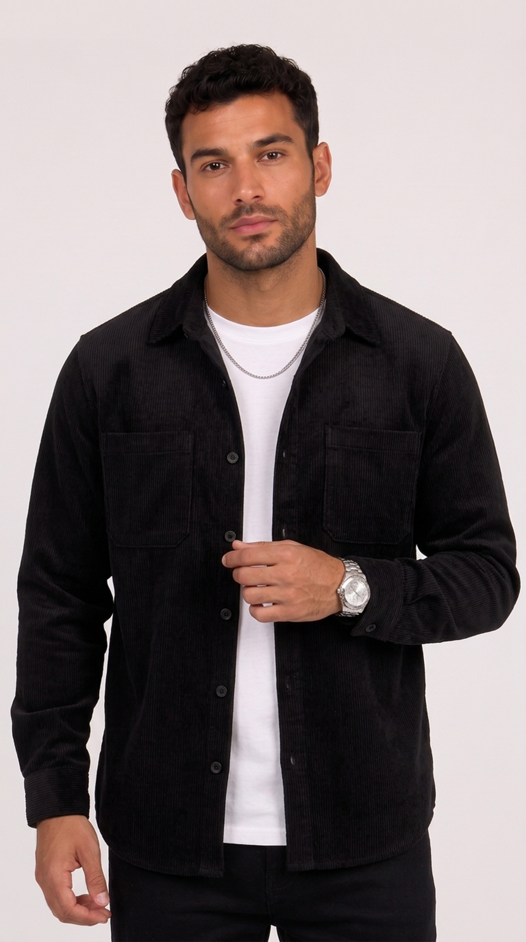 A man wearing a black button-up overshirt over a white t-shirt, standing against a light gray studio background, from Meleche Fashion USA or Meléche (short as (Mé))