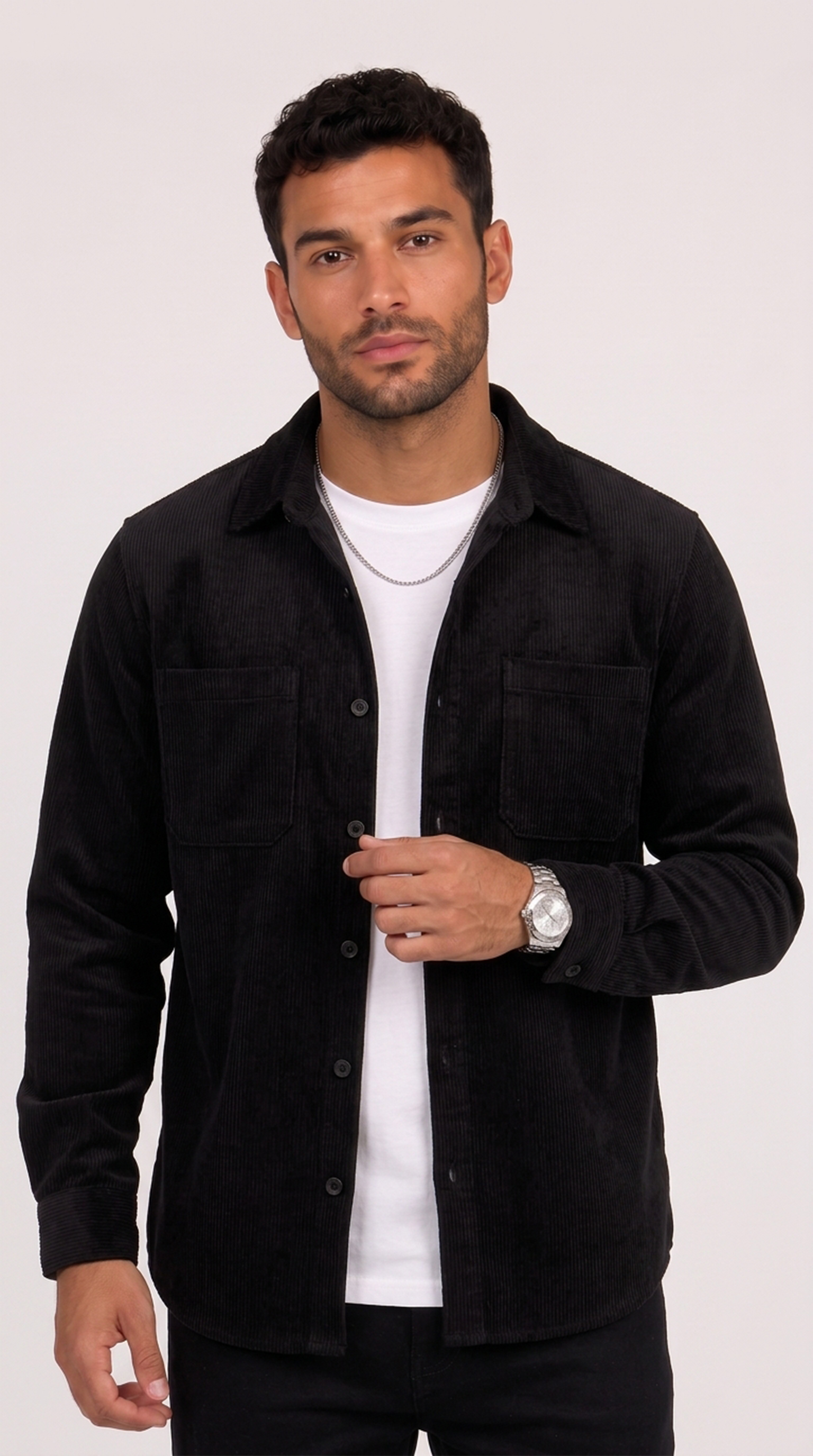 A man wearing a black button-up overshirt over a white t-shirt, standing against a light gray studio background, from Meleche Fashion USA or Meléche (short as (Mé))