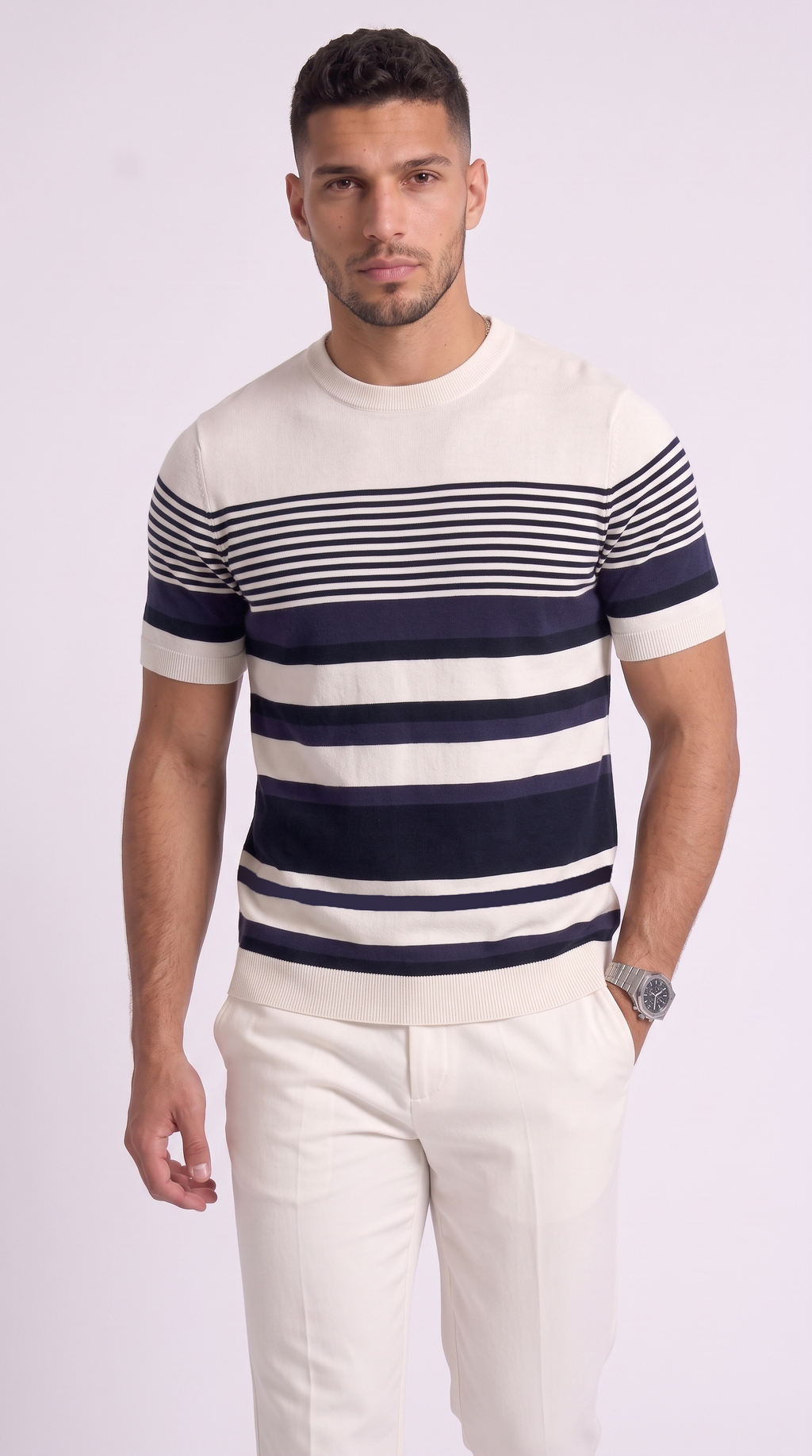 A man wearing a short-sleeve crewneck knit sweater with horizontal navy and off-white stripes, paired with off-white trousers, against a light studio background, from Meleche Fashion USA or Meléche (short as (Mé))