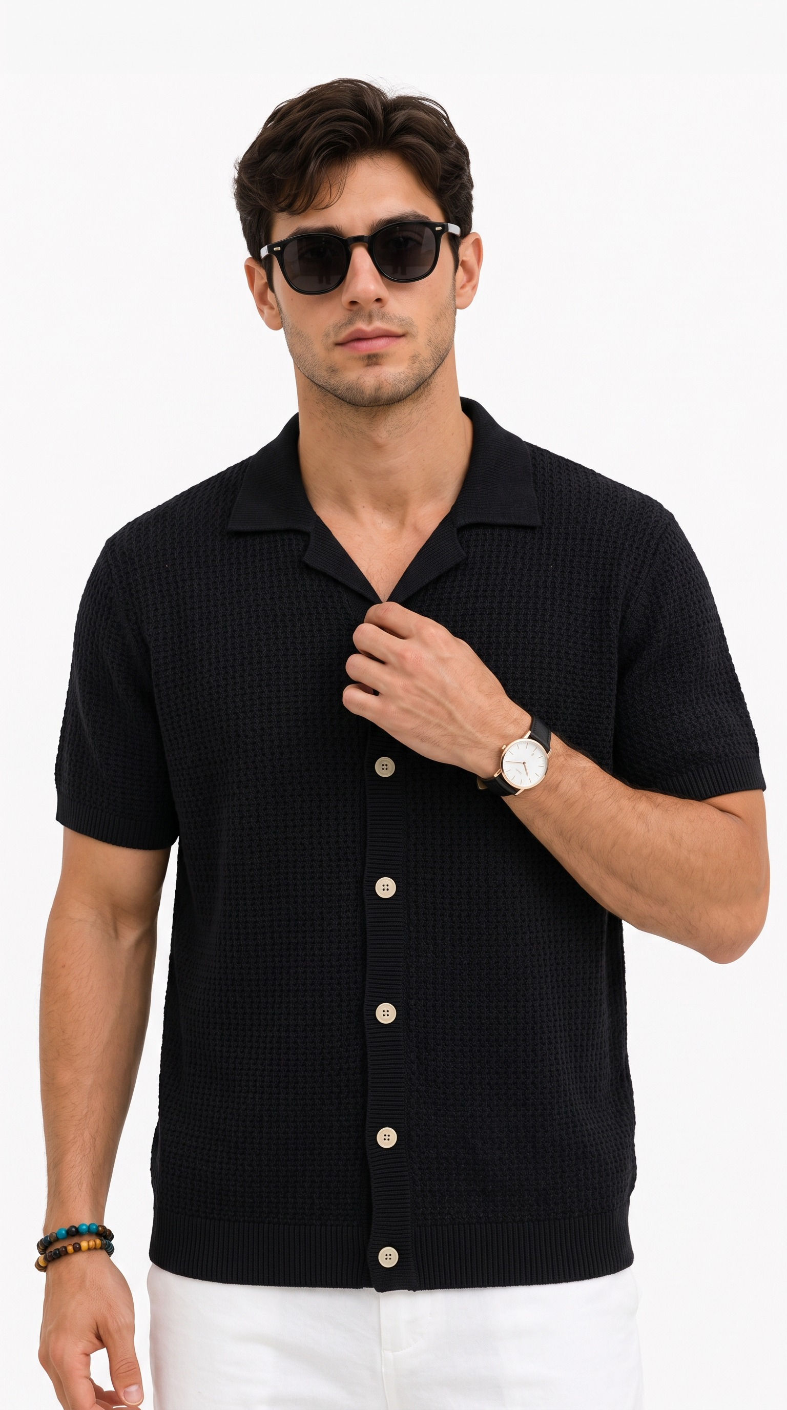 A man wearing a black short-sleeve button-up knit polo shirt with a textured waffle pattern, white pants, and black sunglasses, photographed against a clean white studio background, from Meleche Fashion USA or Meléche (short as (Mé))