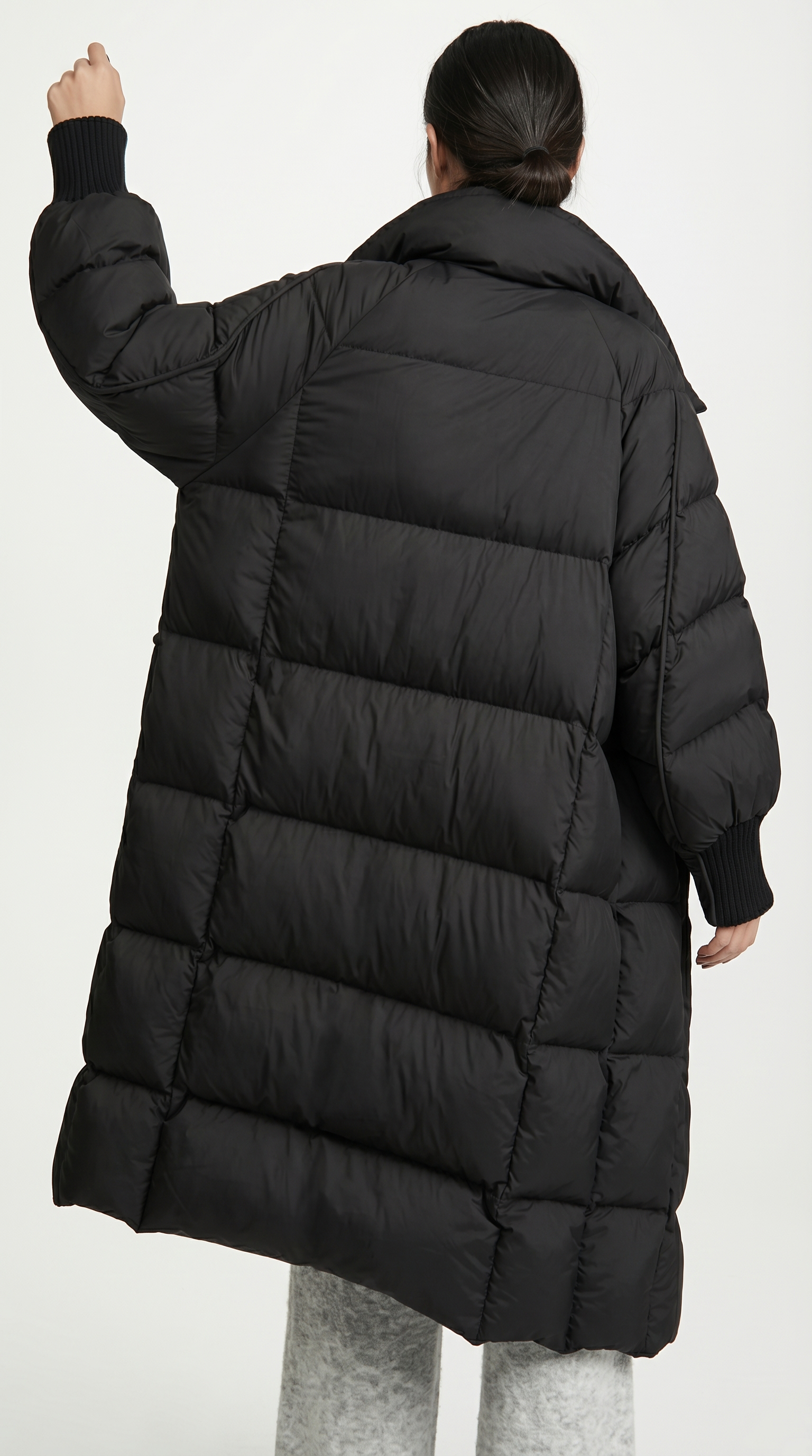 Person wearing a long black puffer coat on a white background from Meleche or Meléche USA (short as (Mé))