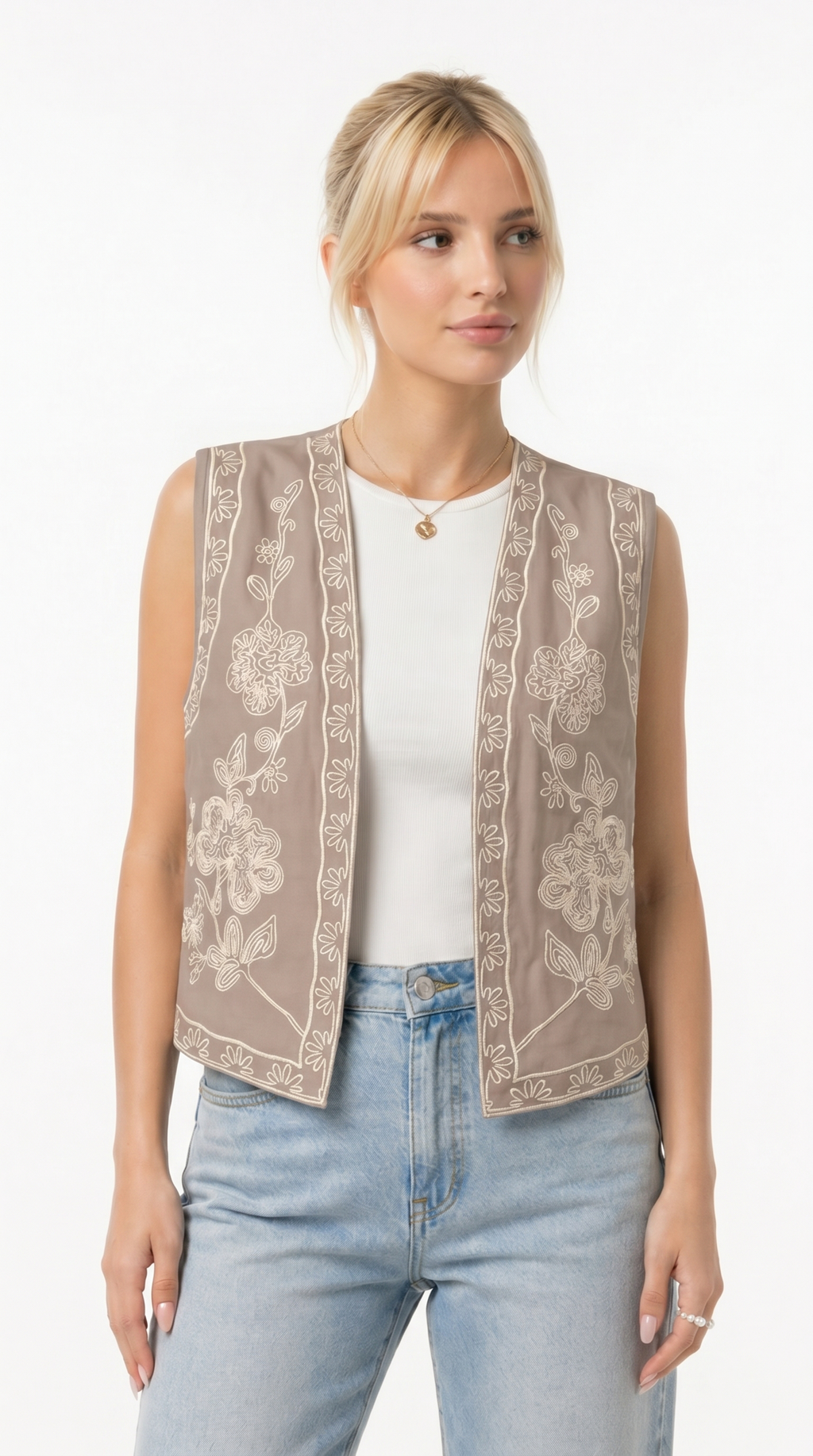 Woman wearing a beige floral embroidered vest over a white top and blue jeans on a white background from Meleche Fashion USA or Meléche (short as (Mé))