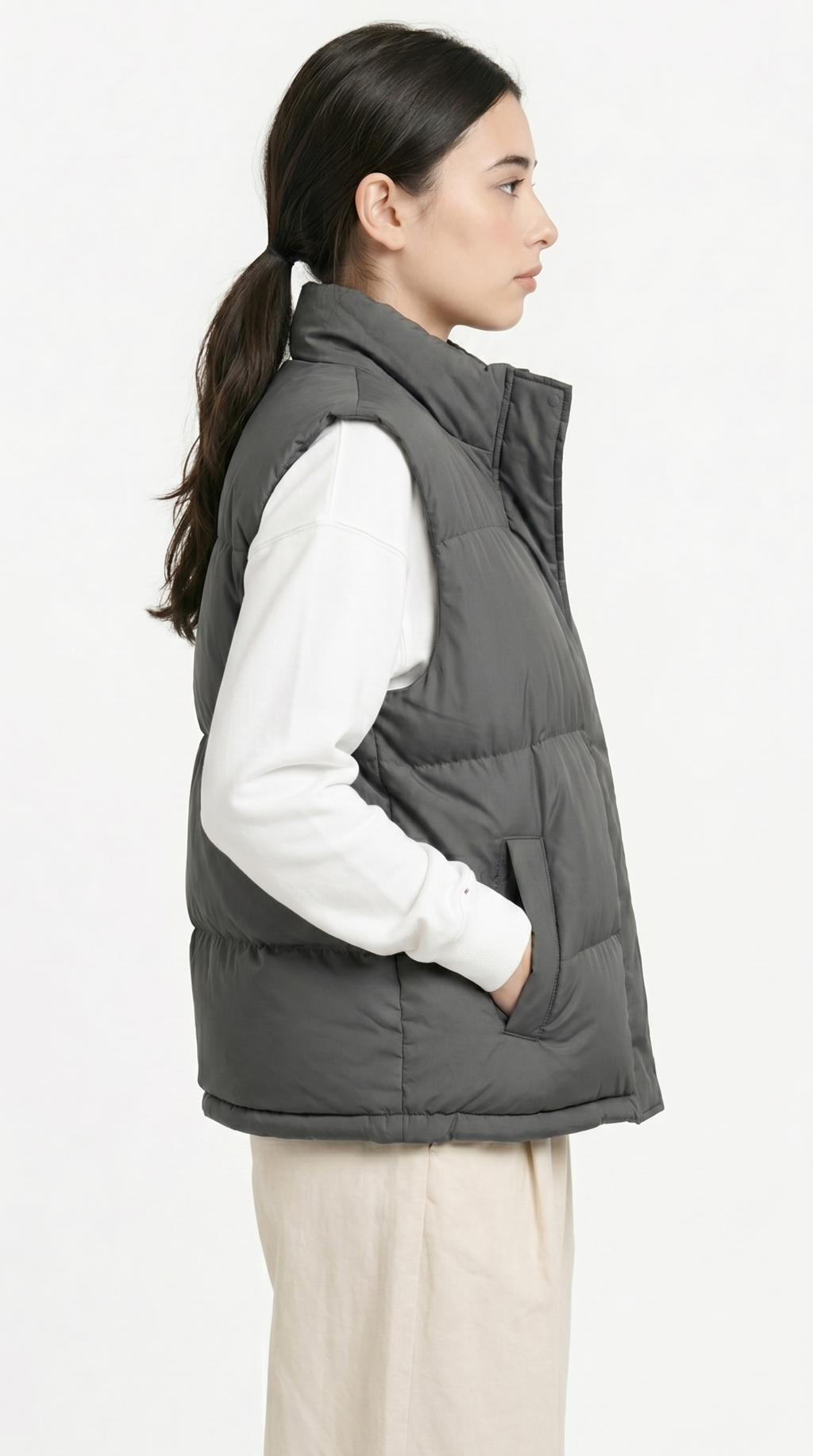 a girl from side view wearing a gray puffer vest over a white shirt on a white background from Meleche Fashion USA or Meléche (short as (Mé))