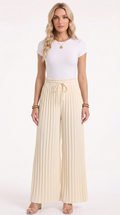 A woman modeling a white short-sleeve top and cream pleated wide-leg drawstring pants against a plain white studio background, from Meleche Fashion USA or Meléche (short as (Mé))