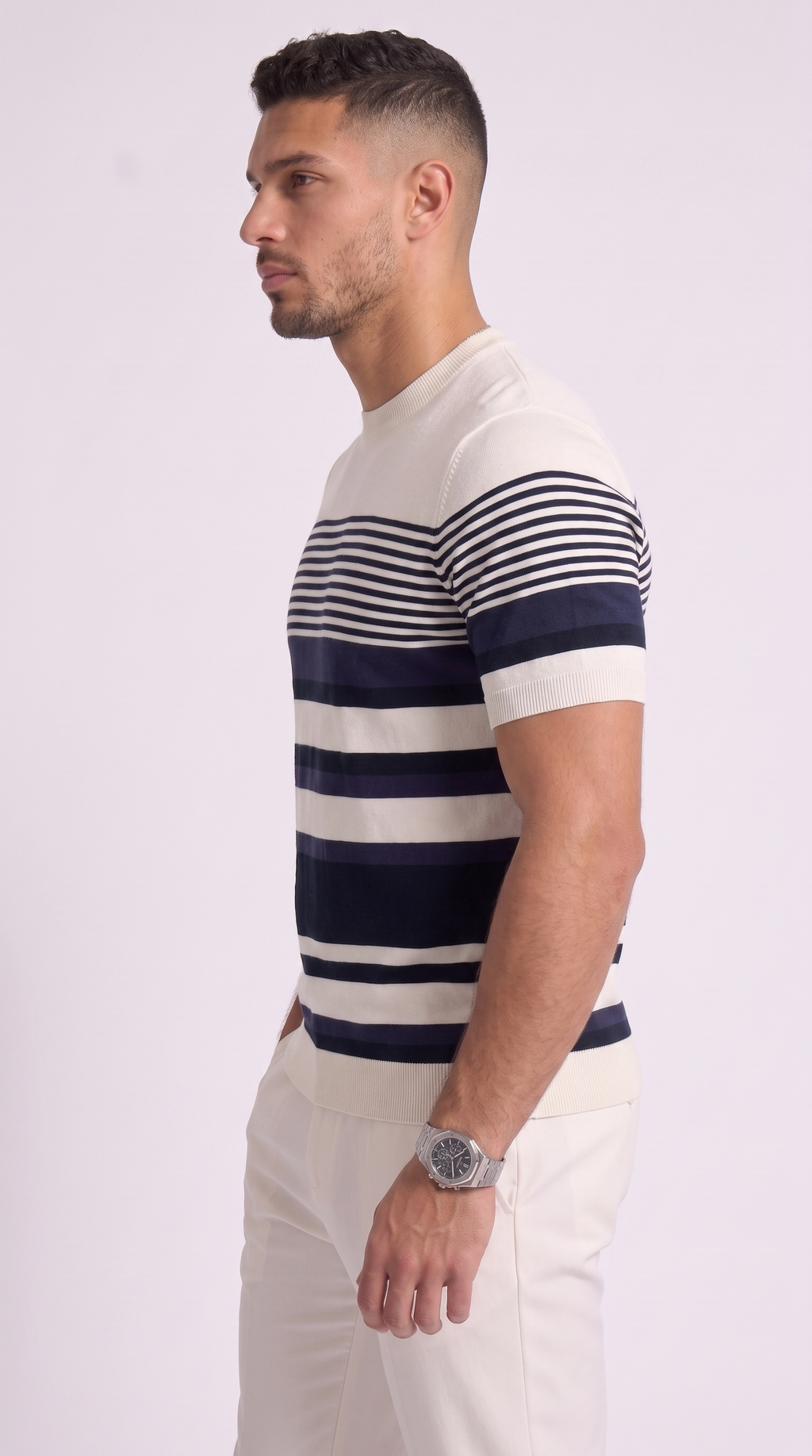 A man in profile wearing a short-sleeve crew-neck knit sweater with horizontal navy and off-white stripes, paired with off-white trousers, against a plain light background, from Meleche Fashion USA or Meléche (short as (Mé))