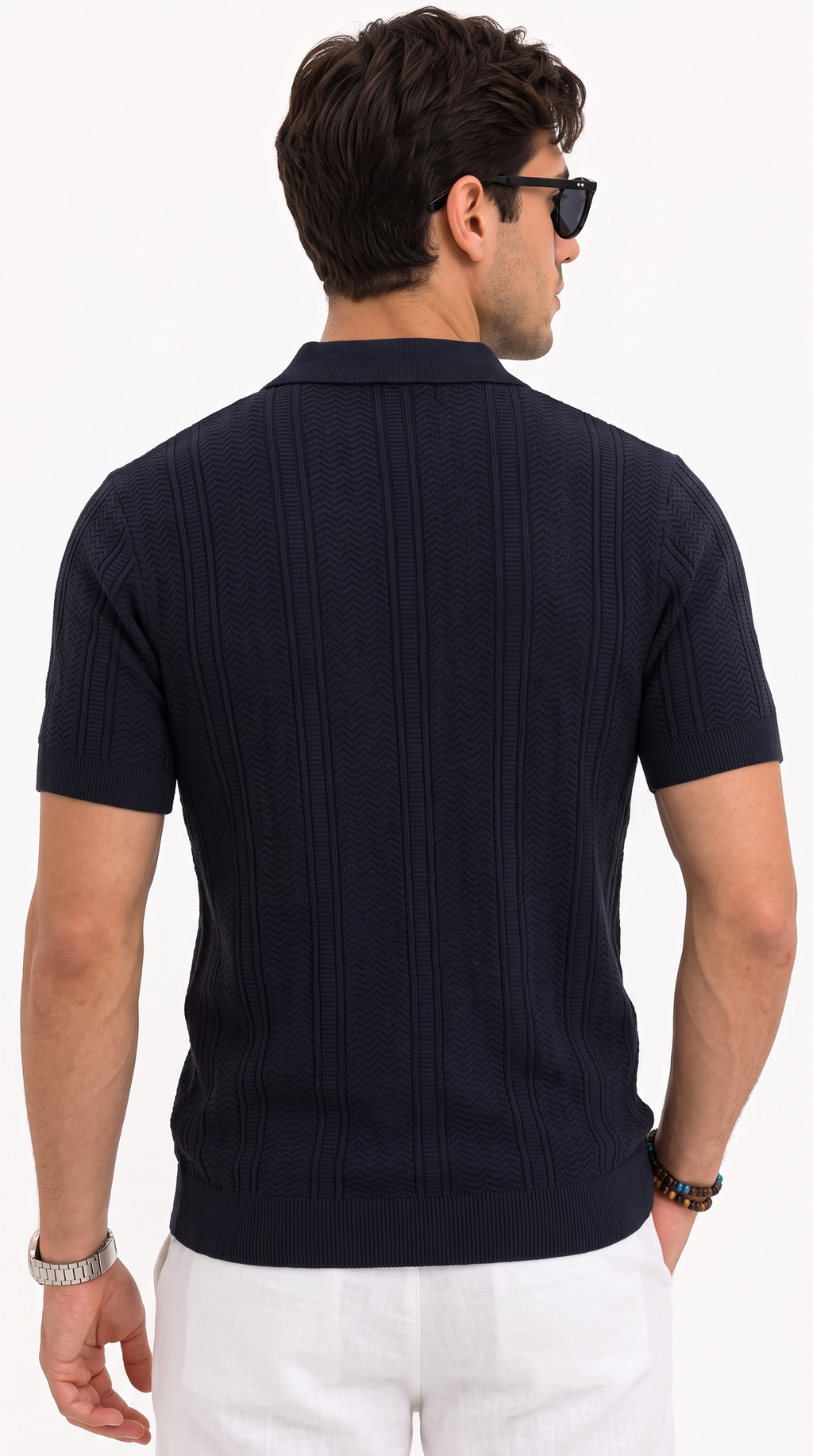 A man shown from the back wearing a dark navy short-sleeve knit polo shirt with a textured vertical pattern, paired with white pants and black sunglasses, against a plain white studio background, from Meleche Fashion USA or Meléche (short as (Mé))