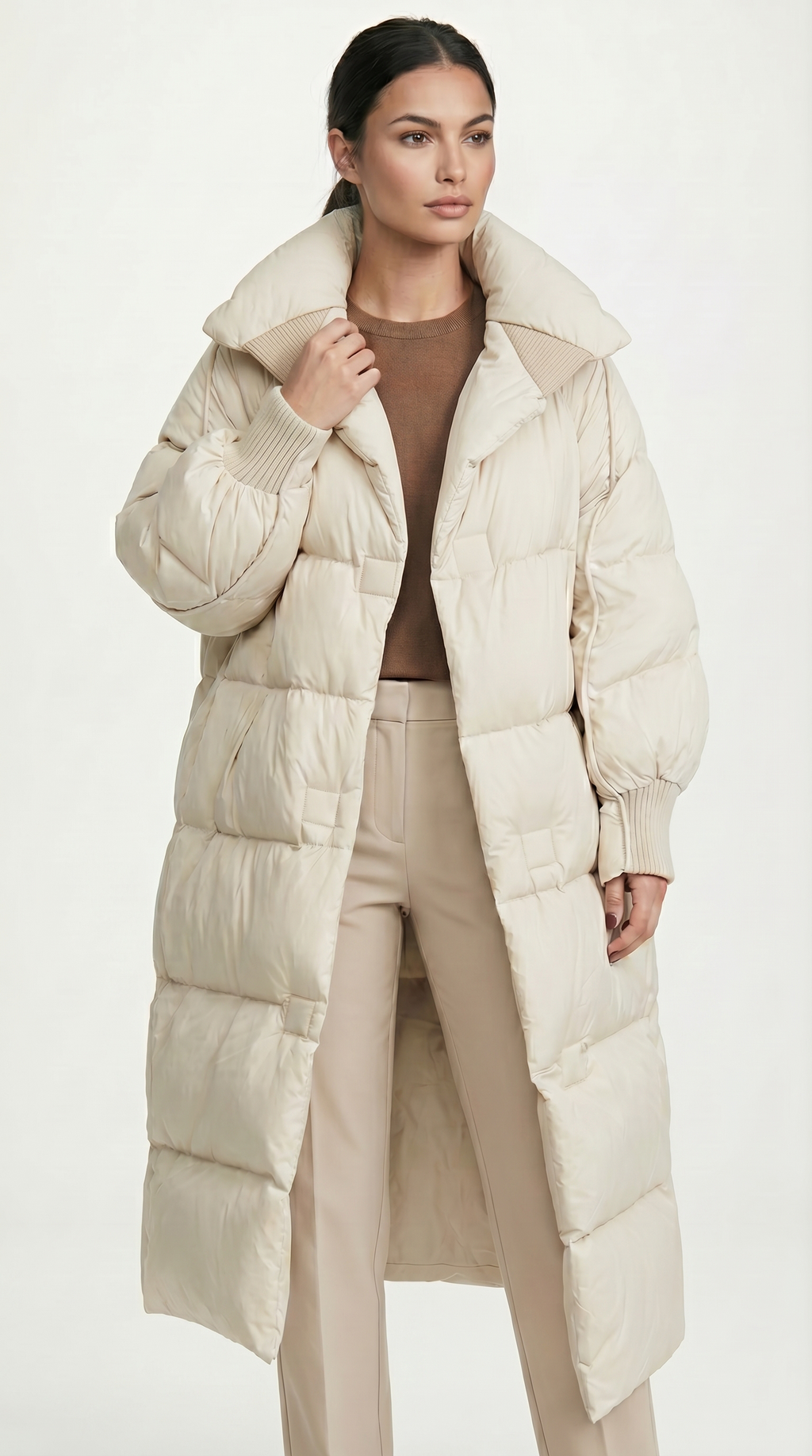 Woman wearing a long beige puffer coat on a white background from Meleche USA or Meléche (short as (Mé))