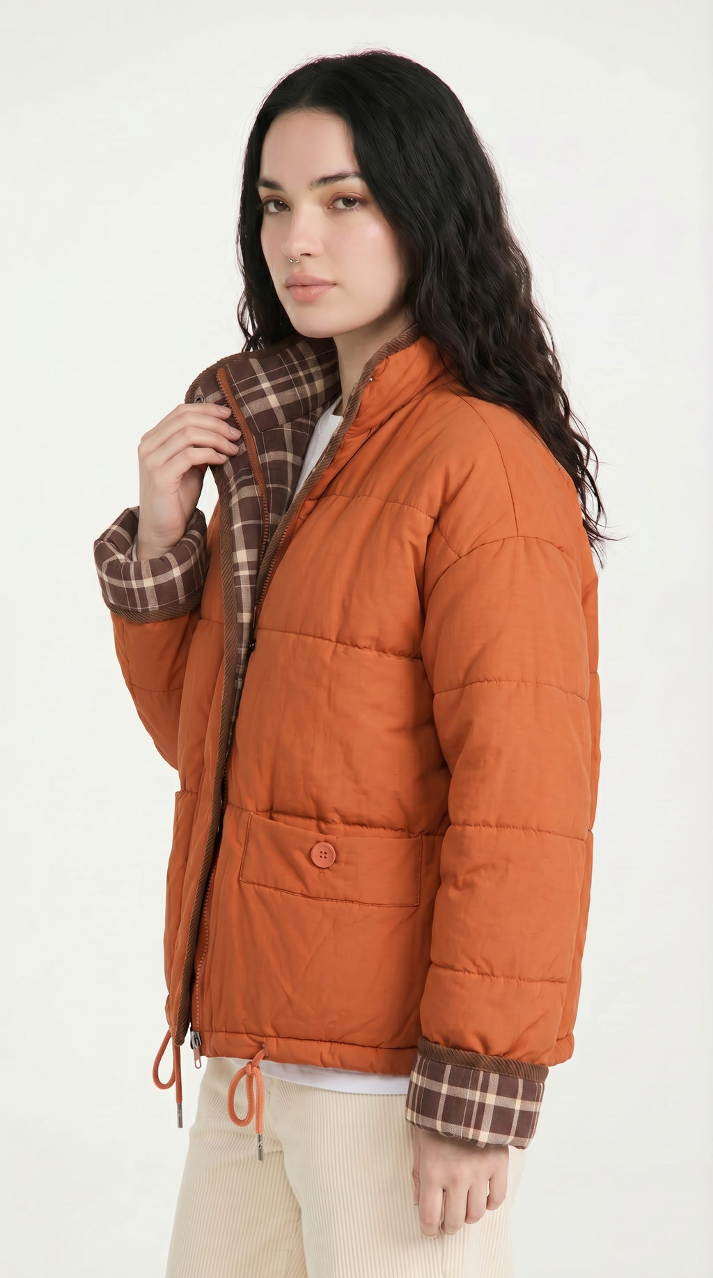Woman wearing an orange puffer jacket with plaid lining on a white background from Meleche or Meléche USA (short as (Mé))
