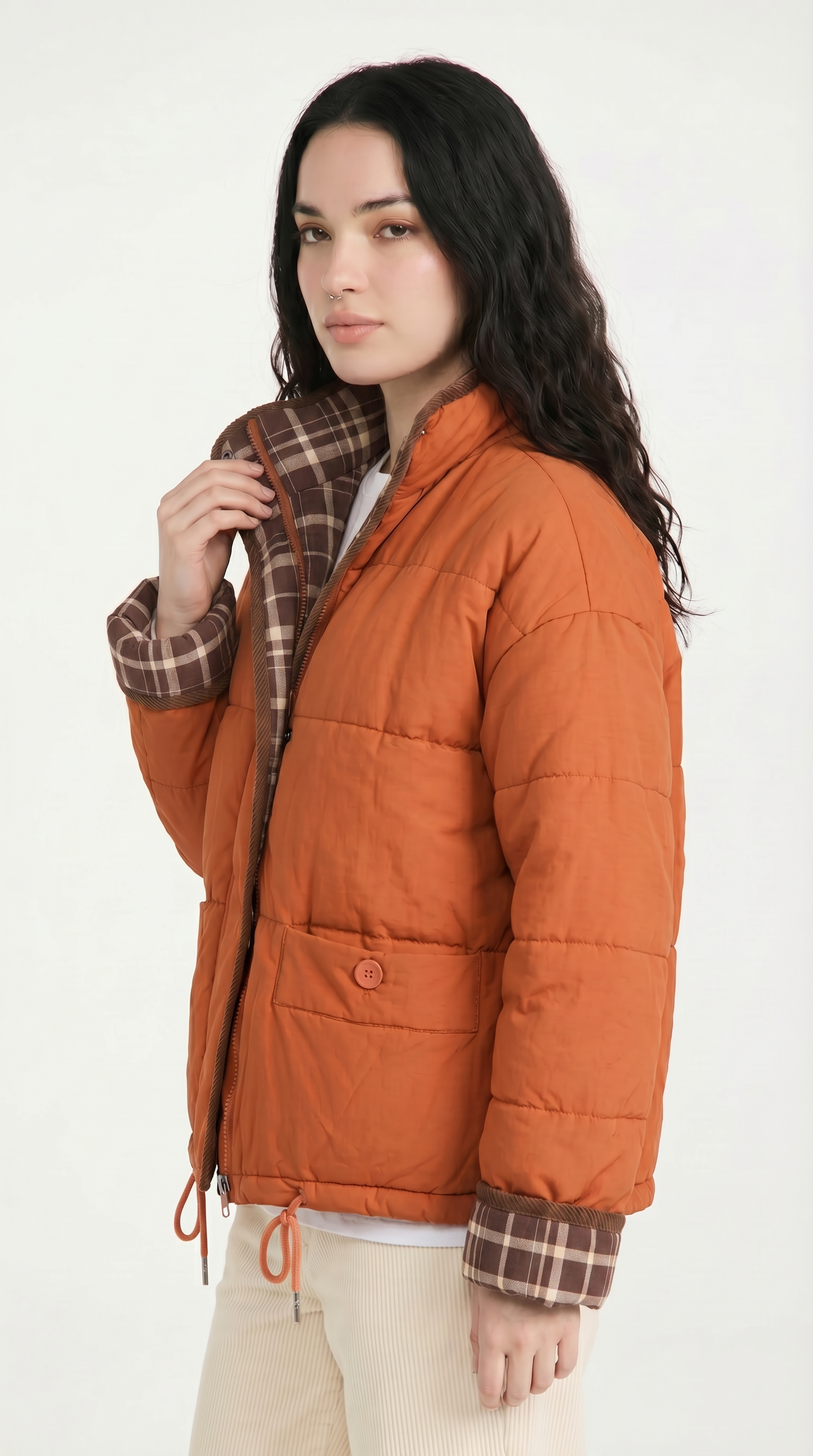 Woman wearing an orange puffer jacket with plaid lining on a white background from Meleche or Meléche USA (short as (Mé))